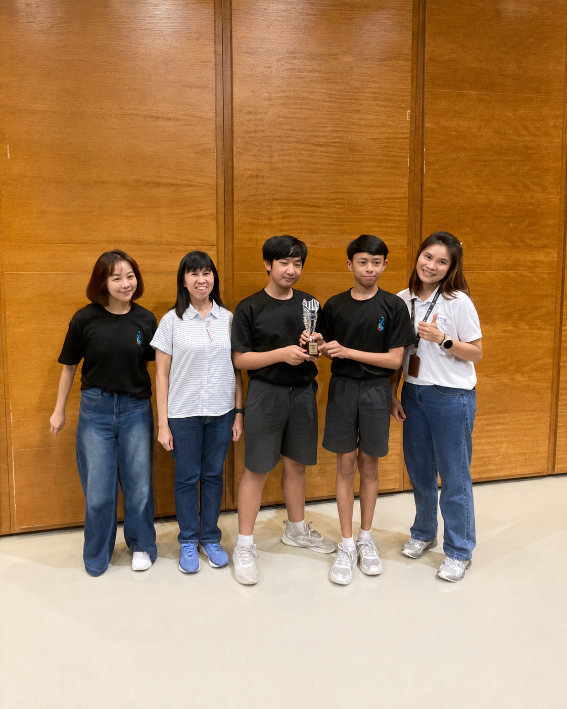 two students holding a trophy pose with three ladies