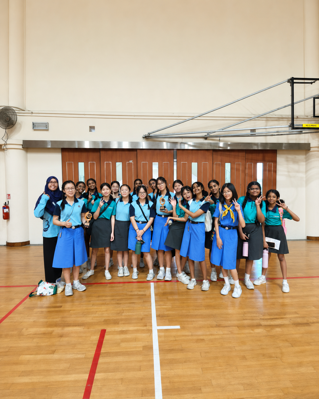 A group of girl guides pose in a Hall with their teachers