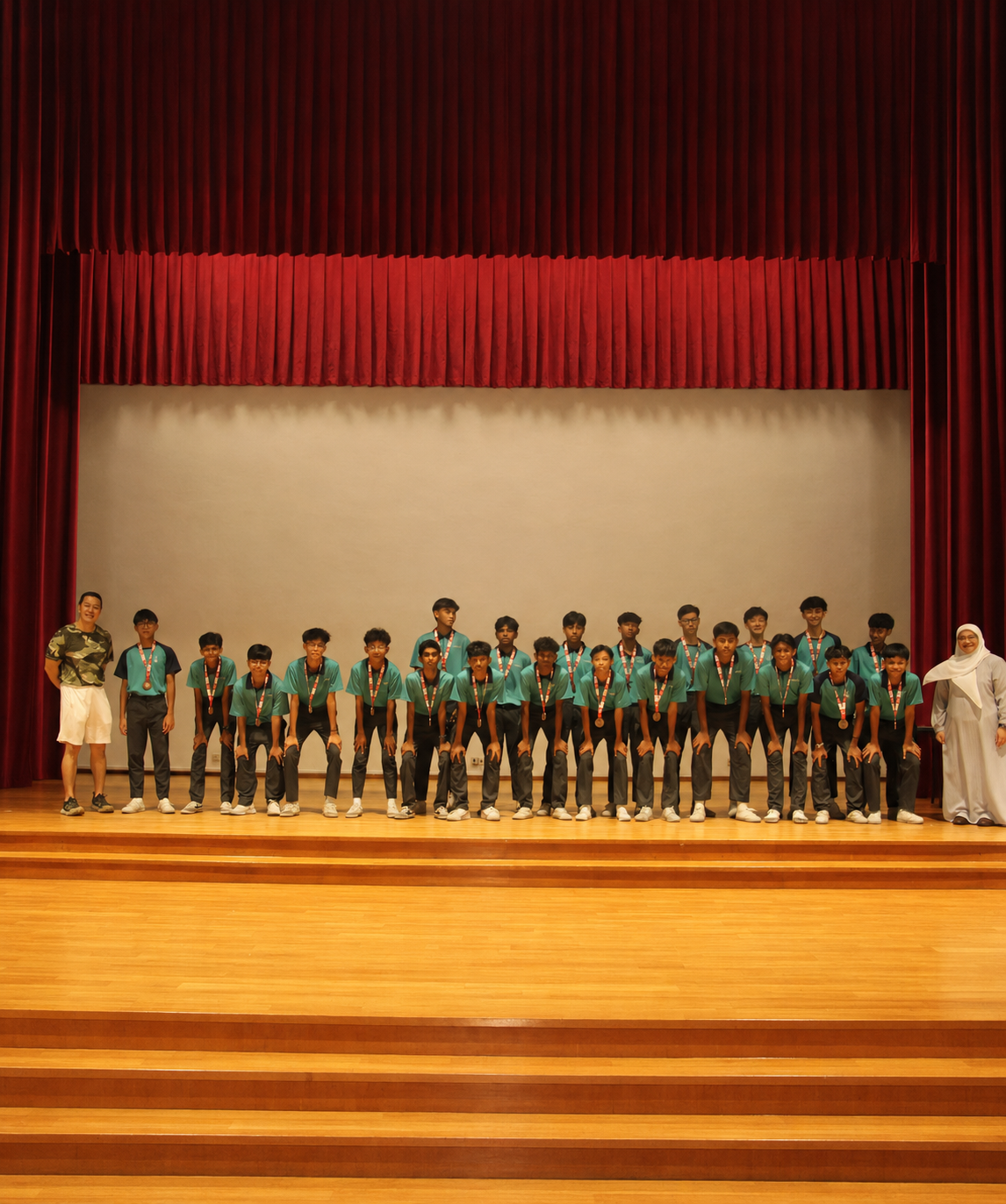 Football team pose with their medals on stage