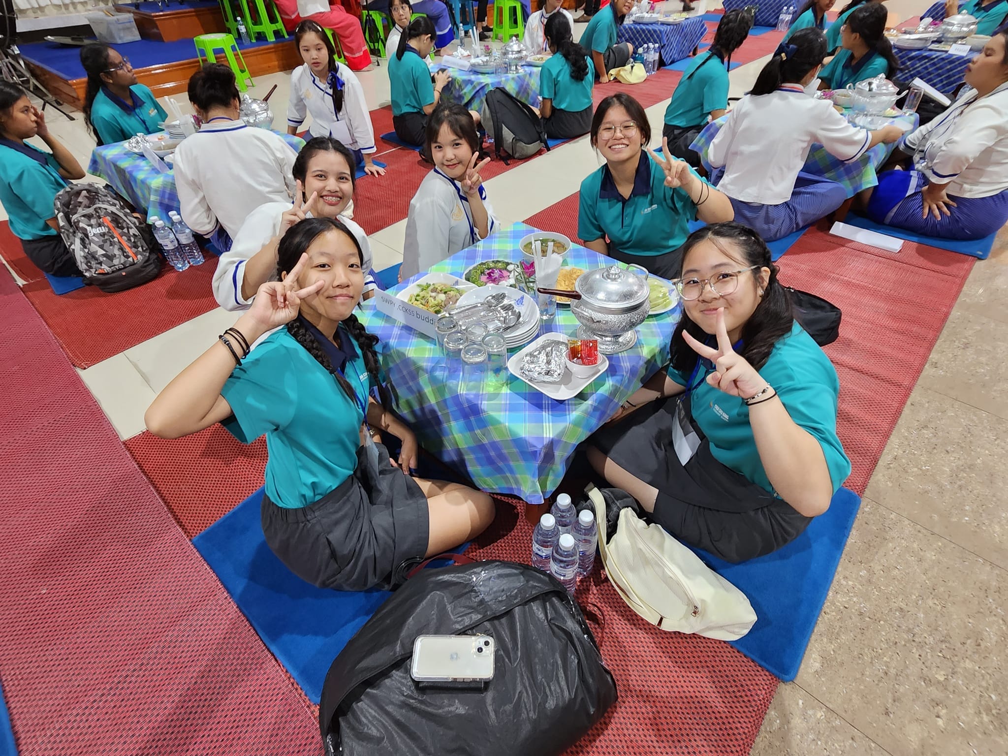 Students and teachers sitting on the floor for a meal.