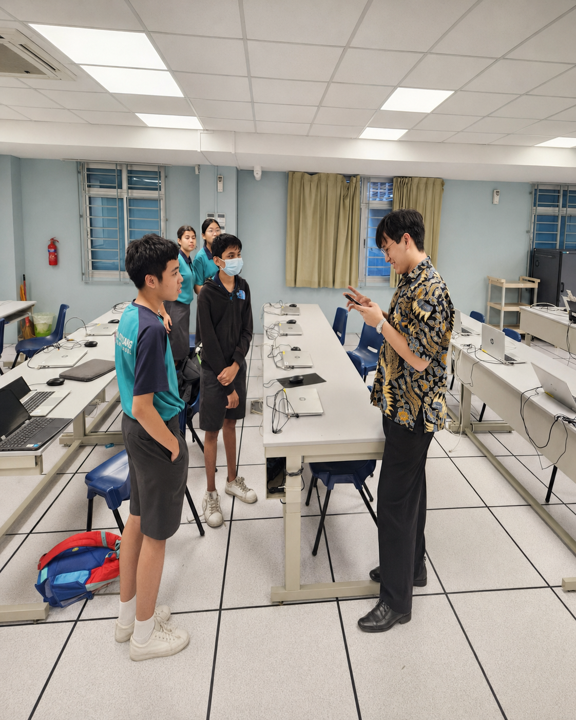 teacher talking to three students in the computer lab