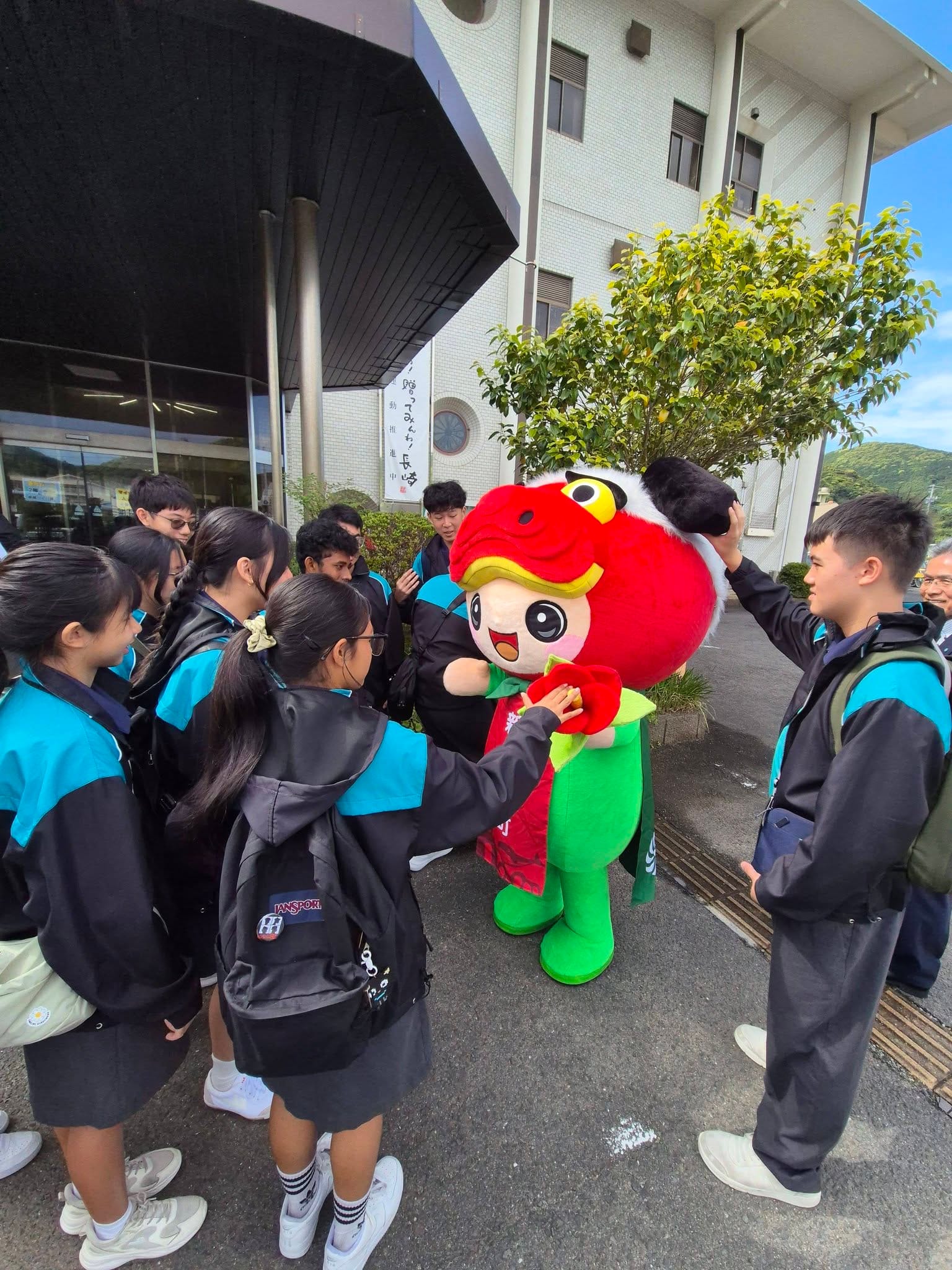 Students surround a red and green mascot