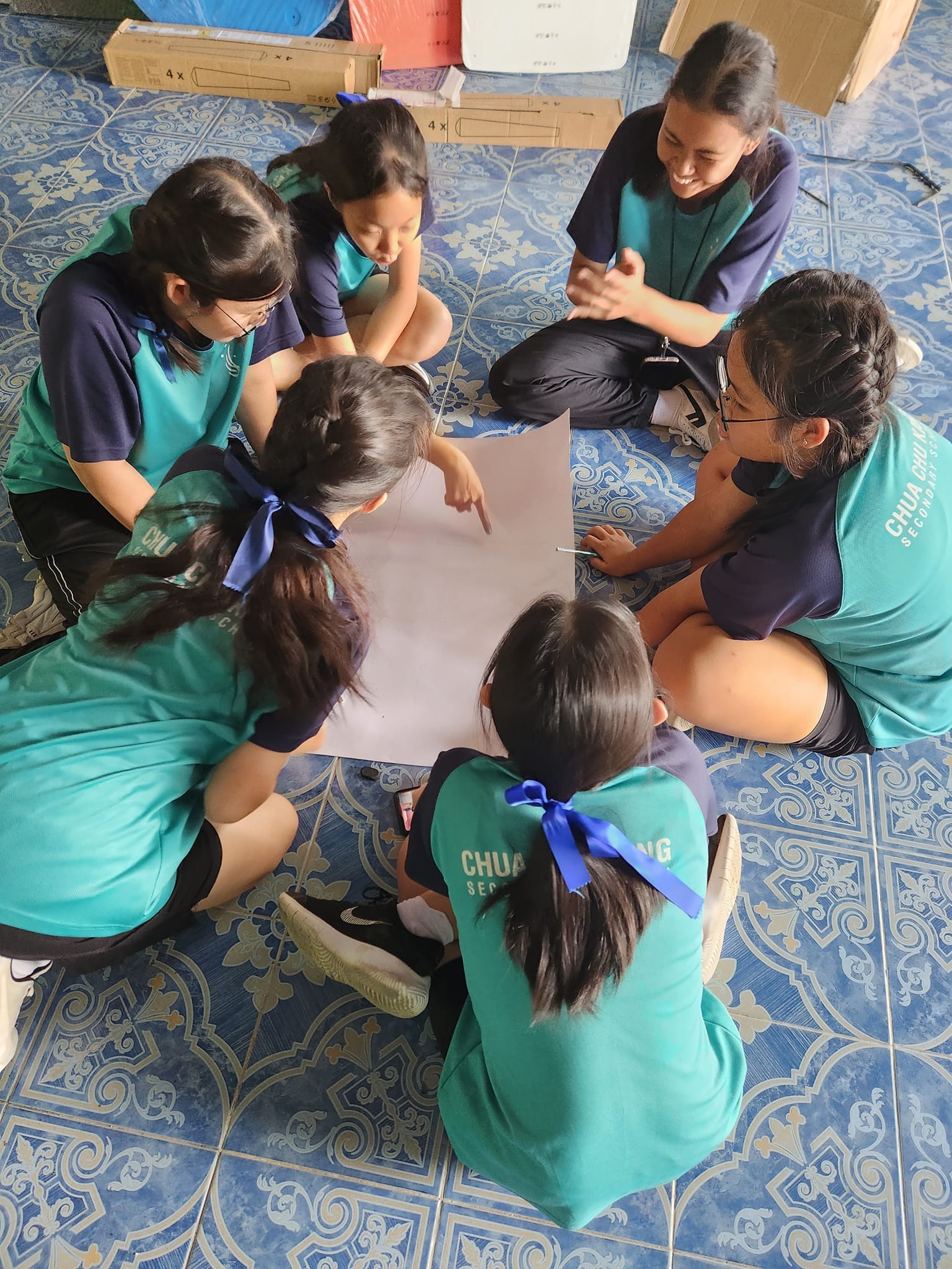 A group of students planning something on the floor using a sheet of paper.