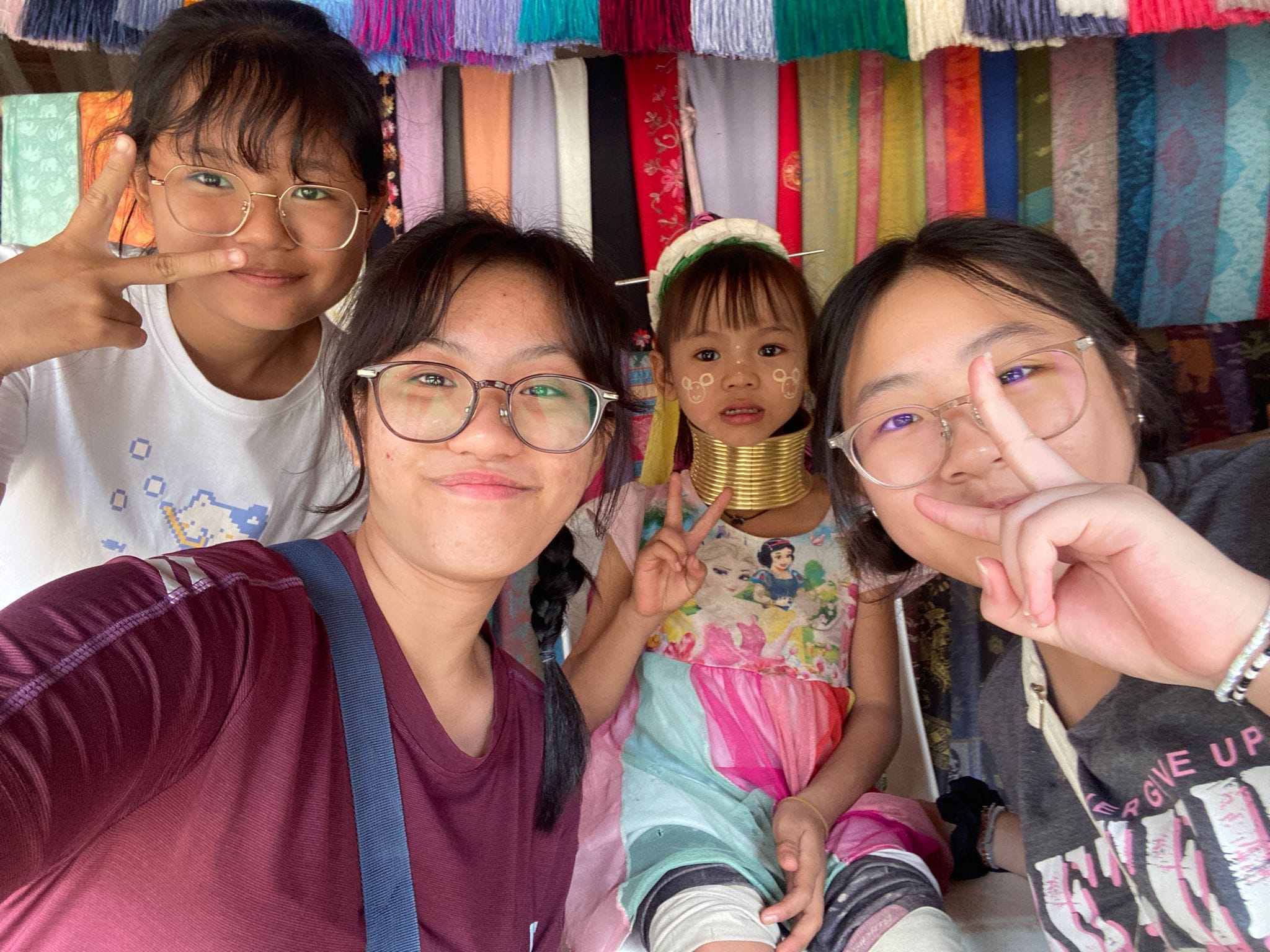 Students posing with a long-necked child.