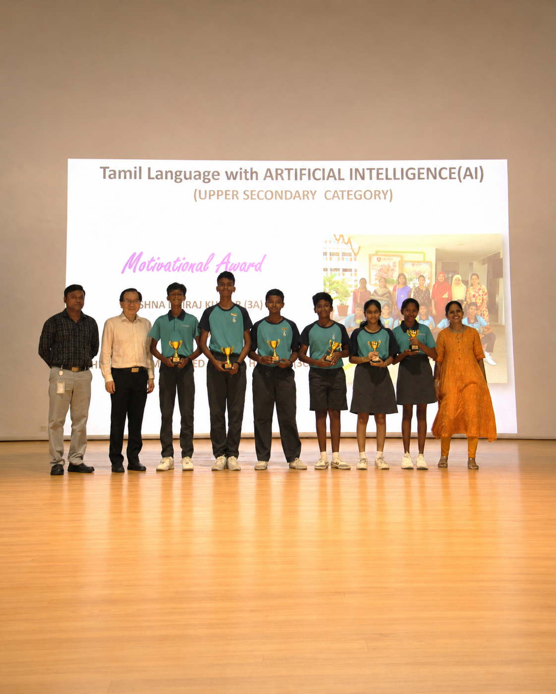 6 students and 3 adults stand on a stage with prizes