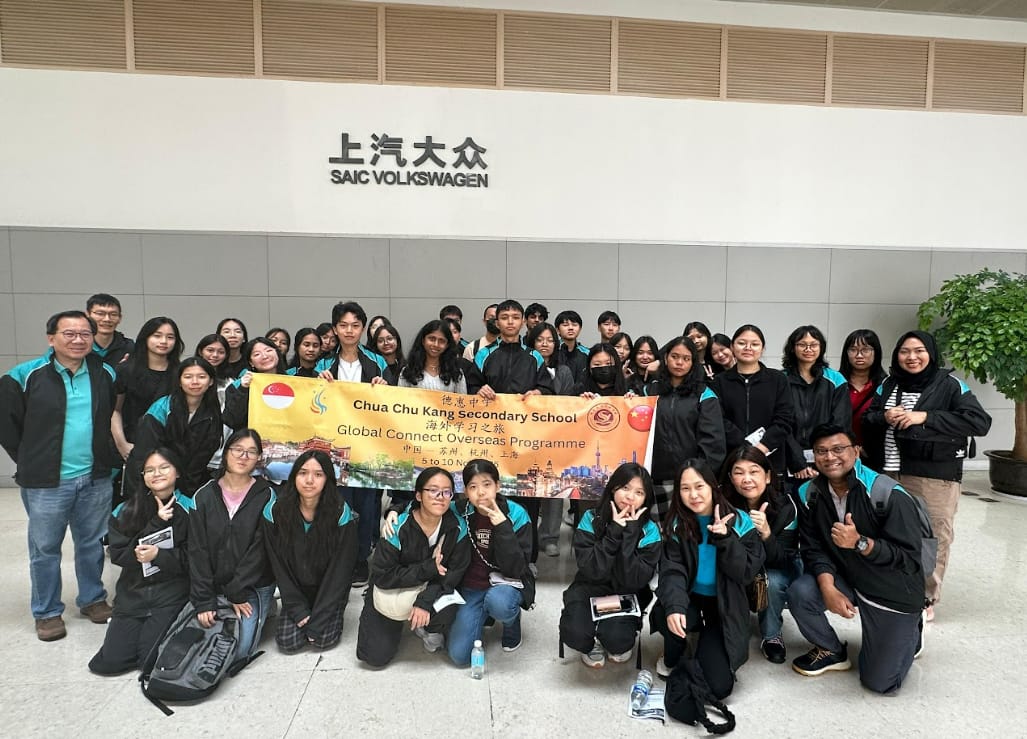 Group of students and teachers from Chua Chu Kang Secondary School posing with a banner at SAIC Volkswagen.