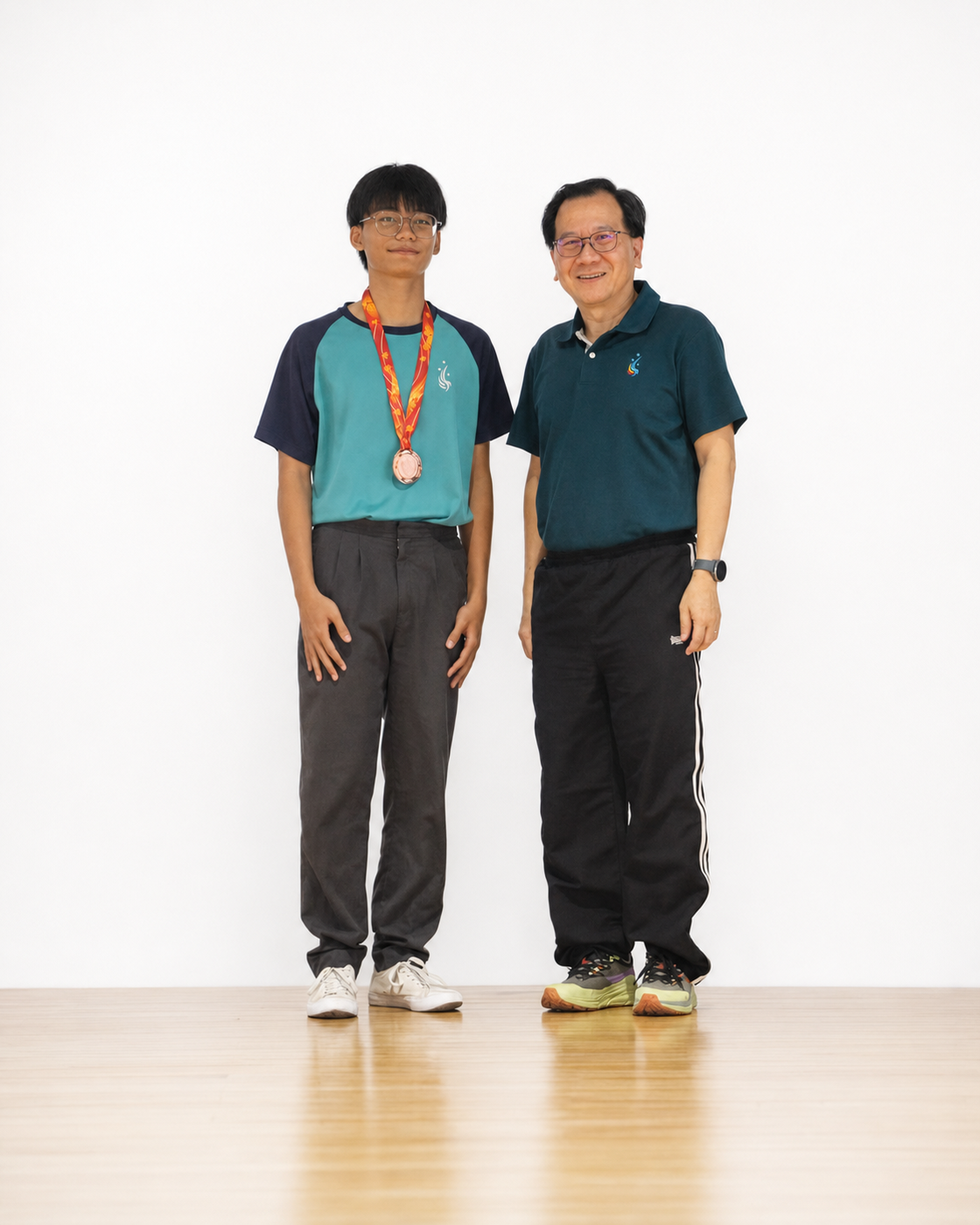 boy with medal stands next to principal on stage