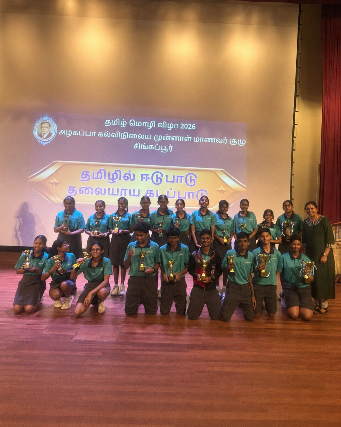 a group of students stand on stage with trophies