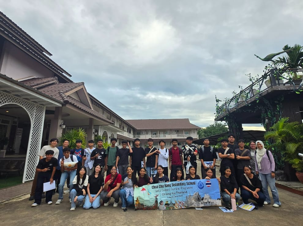 Large student group poses outdoors holding a Chua Chu Kang Secondary School Chiang Rai Thailand banner.
