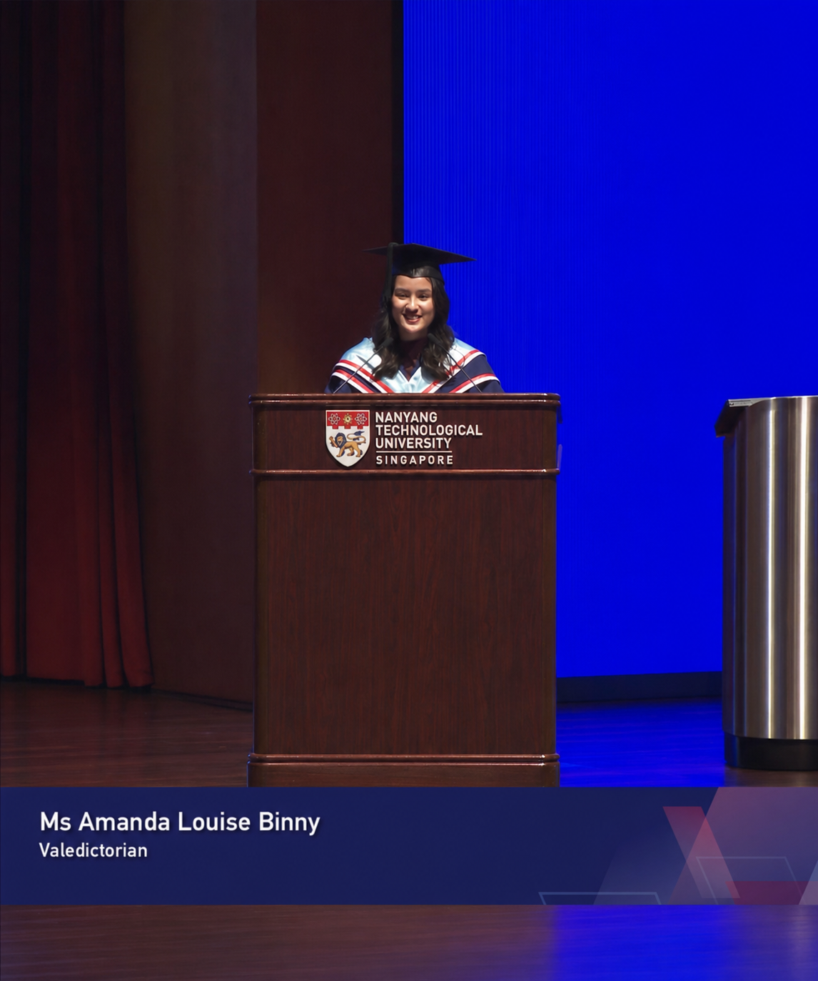 A girl with graduation gown speaks to an audience