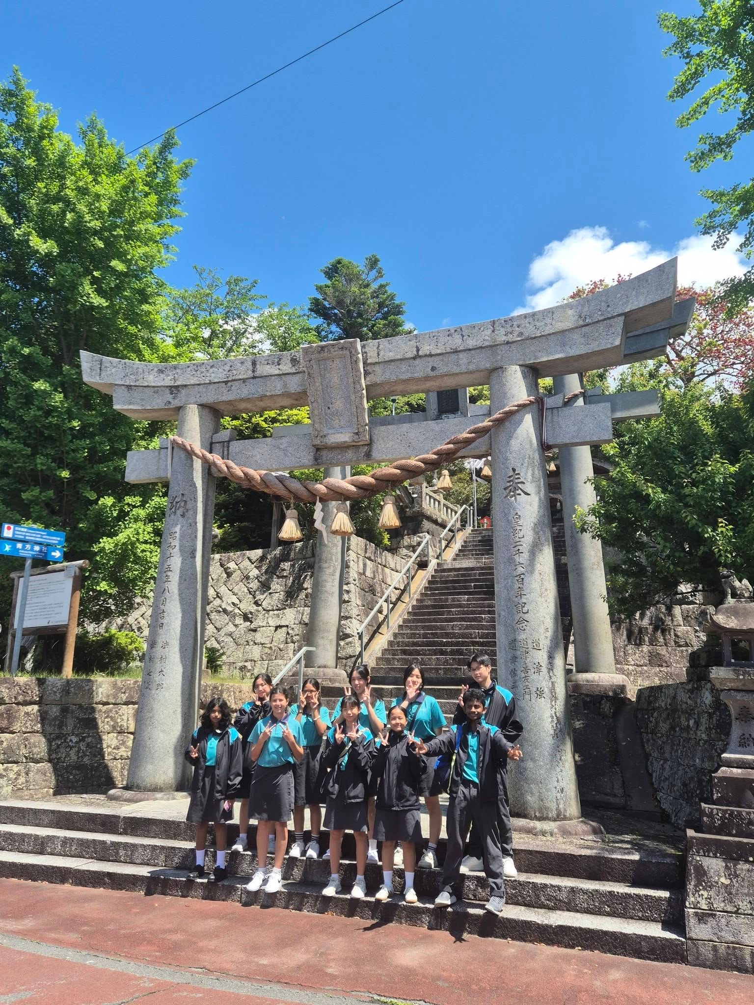 A group of students stand in front of a Torii Gate