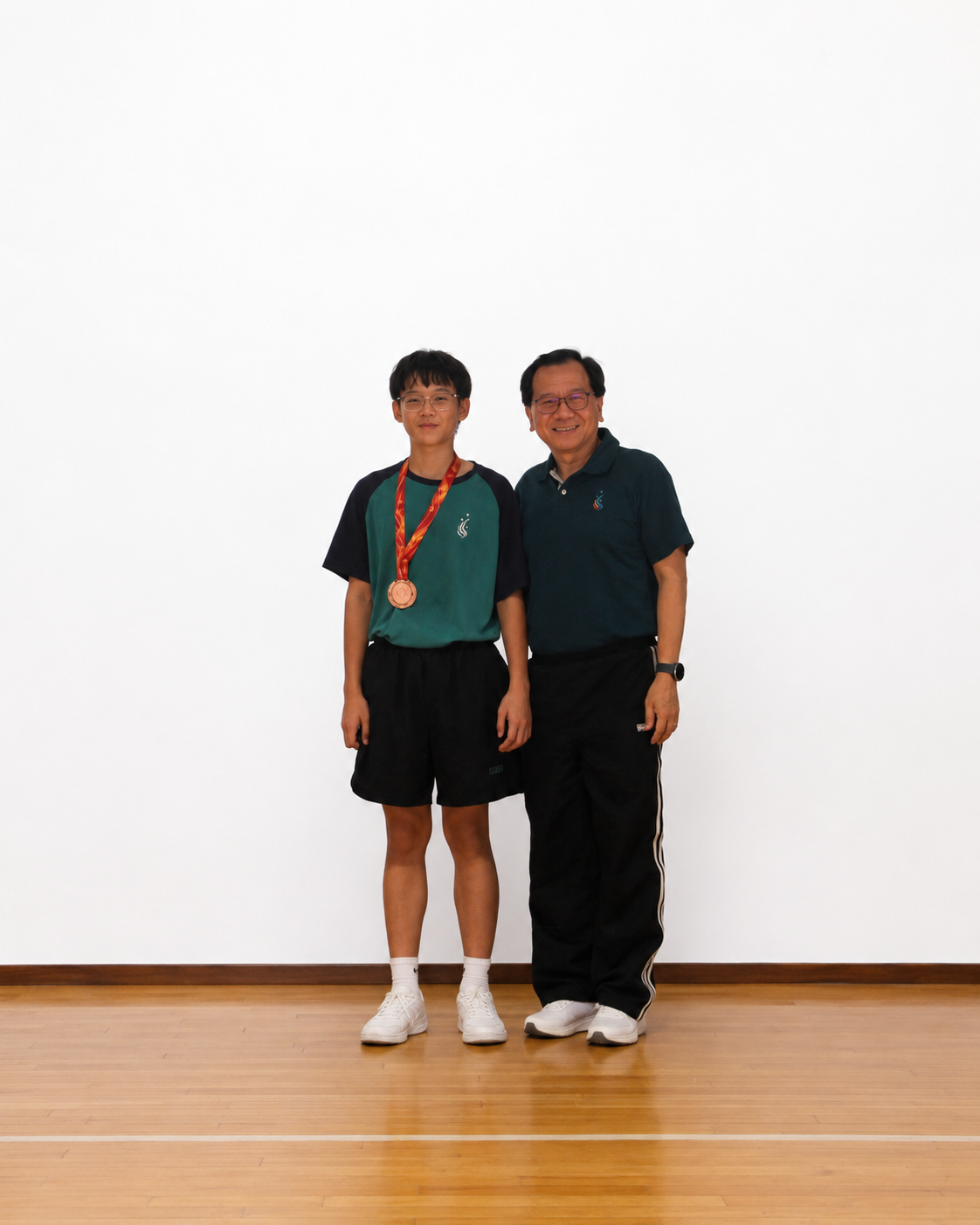 boy stands on a stage with a medal next to principal