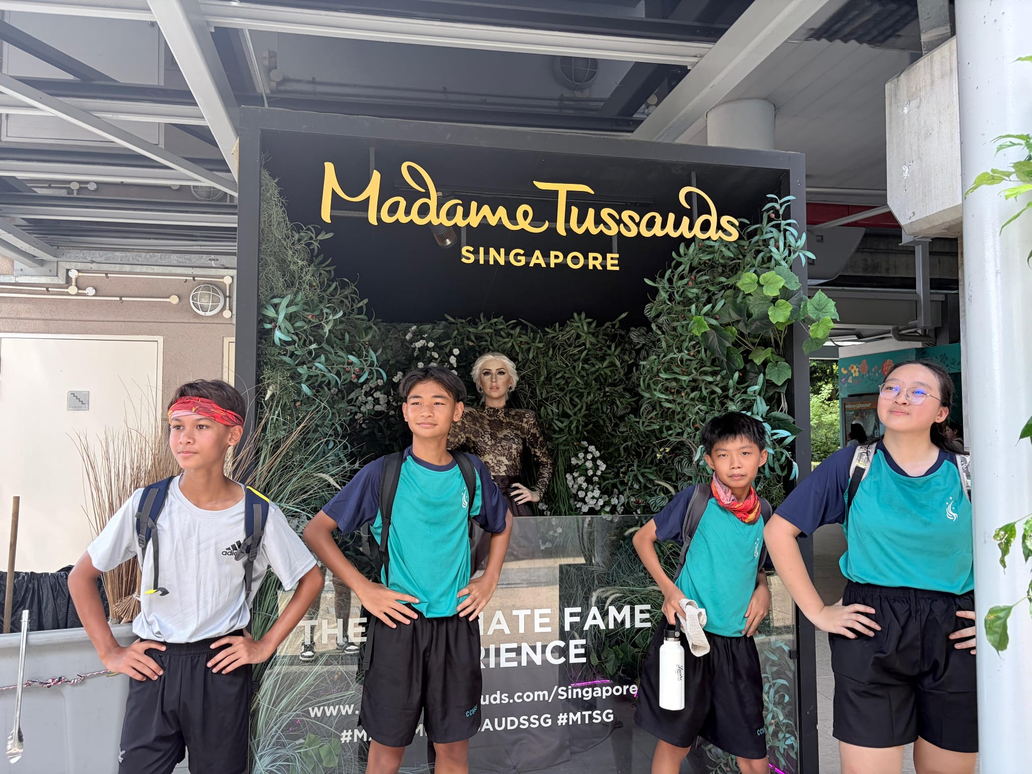 4 students posing before a sign for Madame Tussaud's Singapore