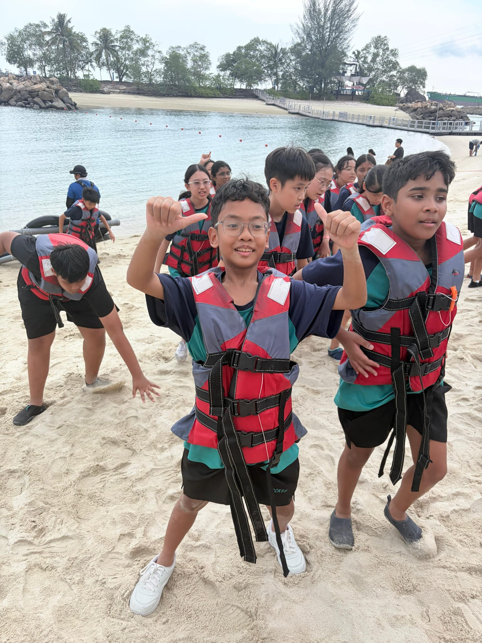 students doing thumbs up at the beach
