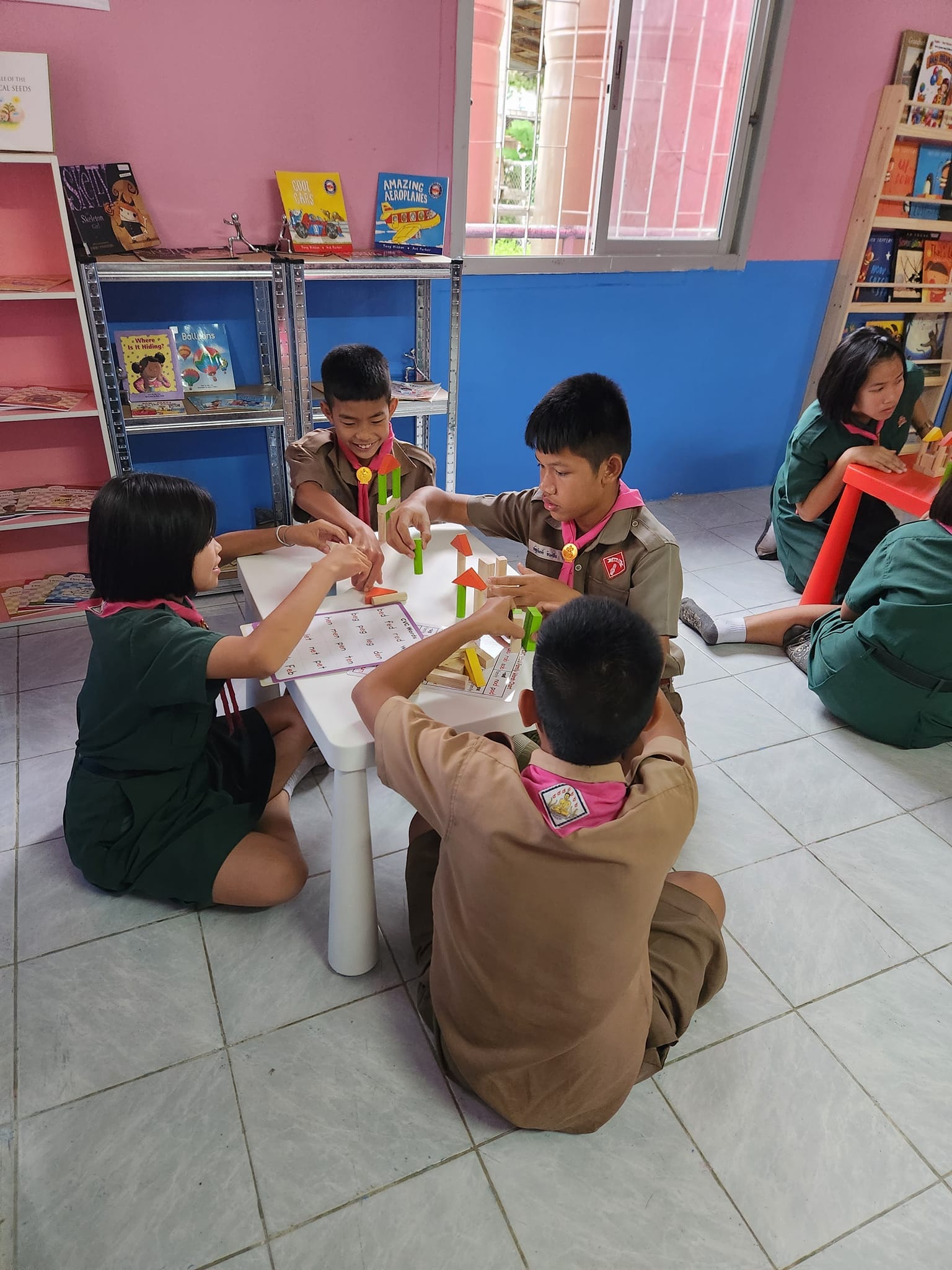 Four students playing with coloured blocks on a low table.