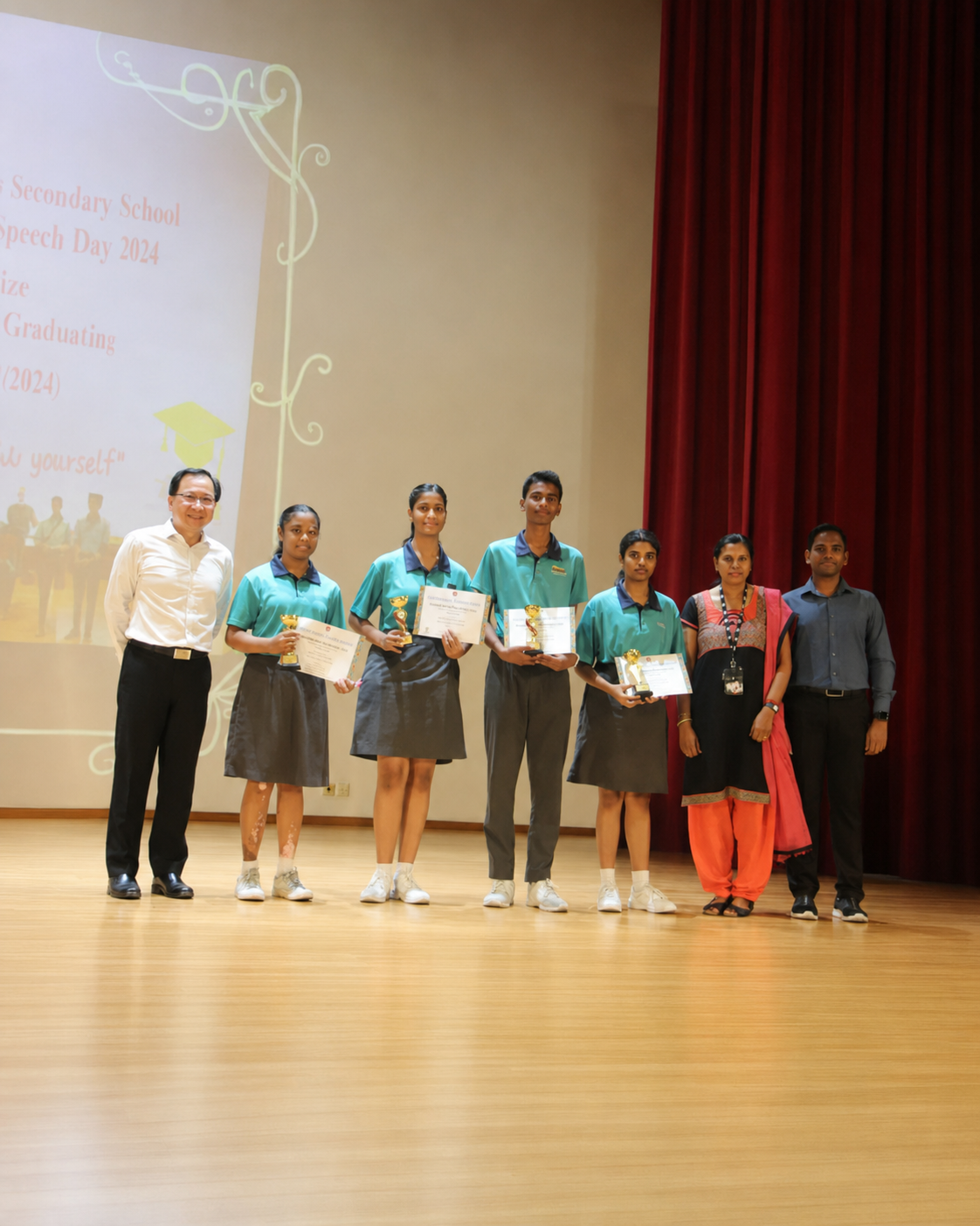 4 students and 3 adults standing on stage