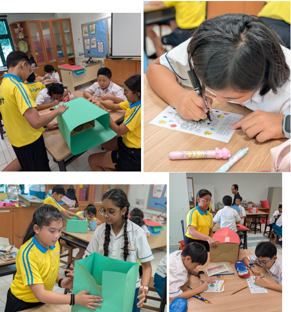 Students in yellow uniforms work on craft projects with green cardboard and drawings in a classroom.