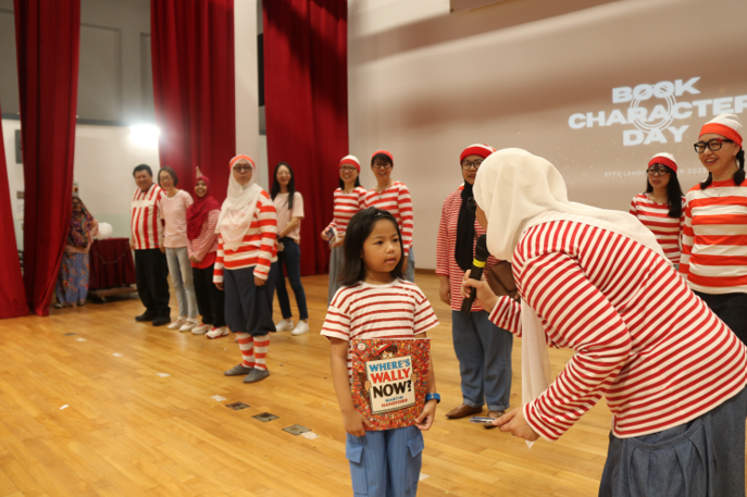 Group of people in red and white striped Where's Wally costumes at a Book Character Day event in a hall.