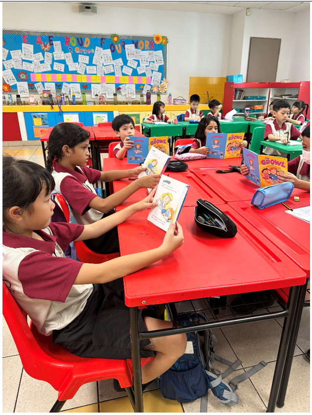 Young students in uniforms sit at red desks in a colorful classroom, reading books titled Growl.