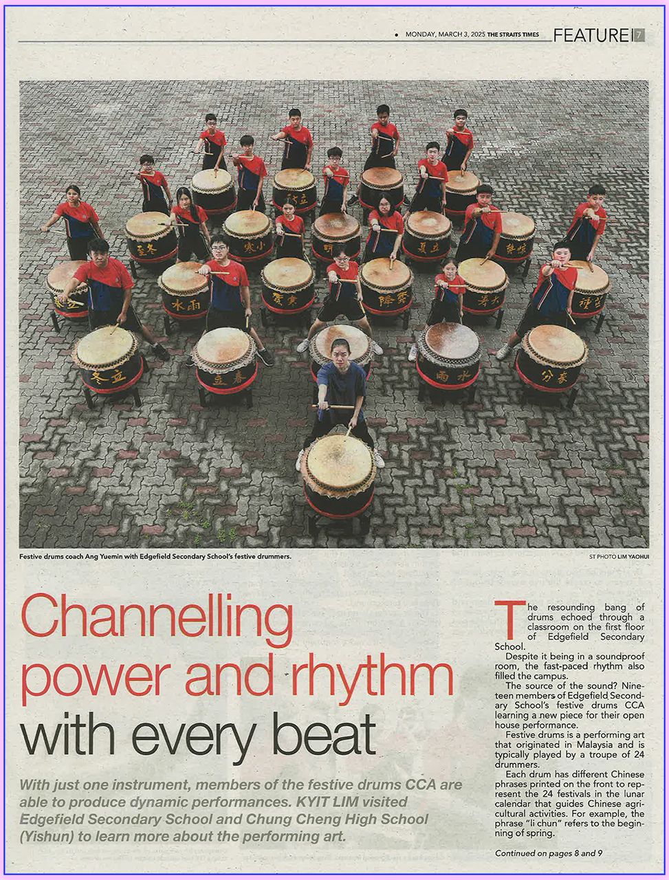 Newspaper feature showing a group of students in red uniforms posed around large Chinese festive drums on a brick courtyard.