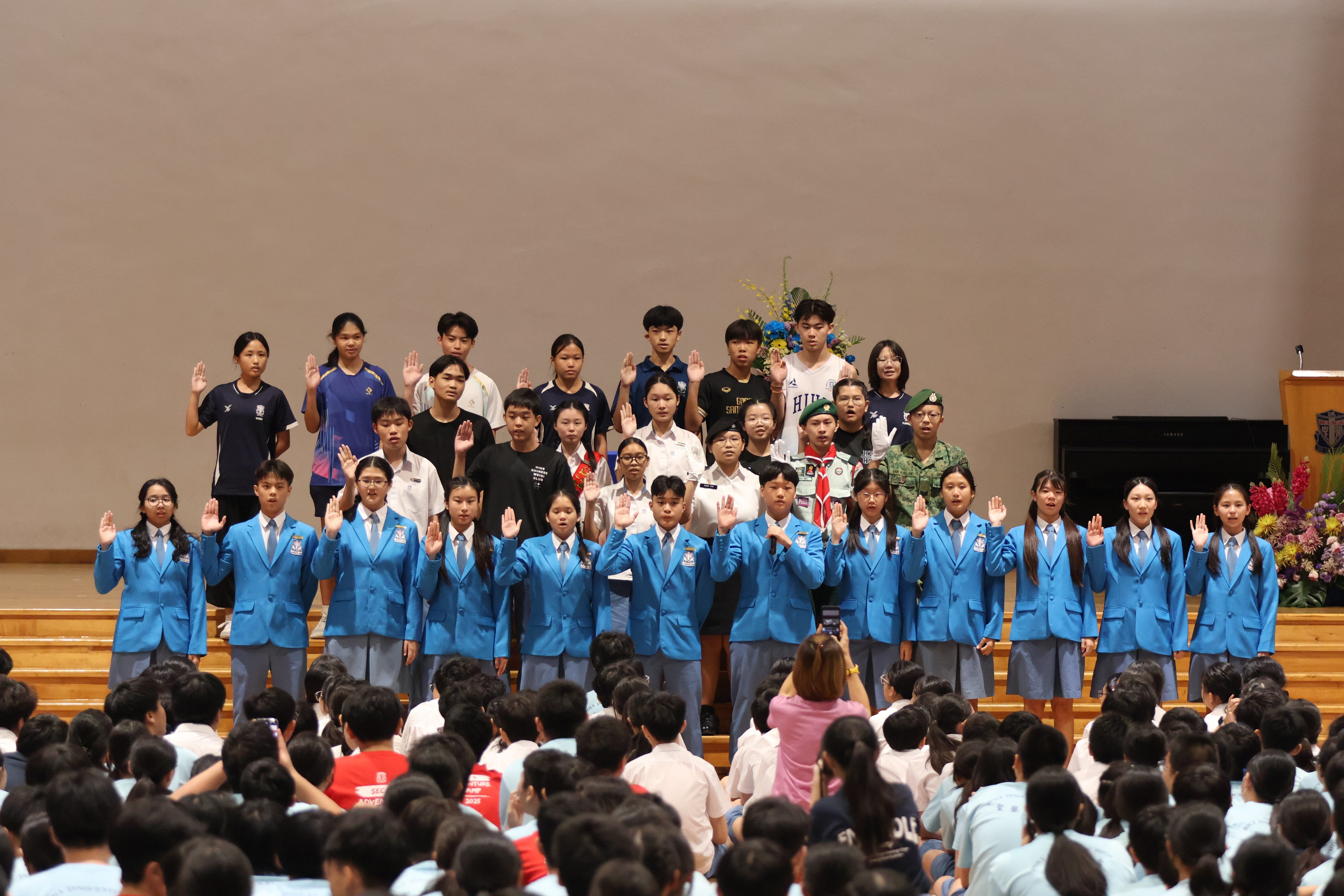 Students on stage with one hand raised up