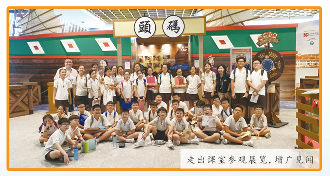 A large group of uniformed school students pose with teachers inside a museum exhibit featuring Chinese signage.