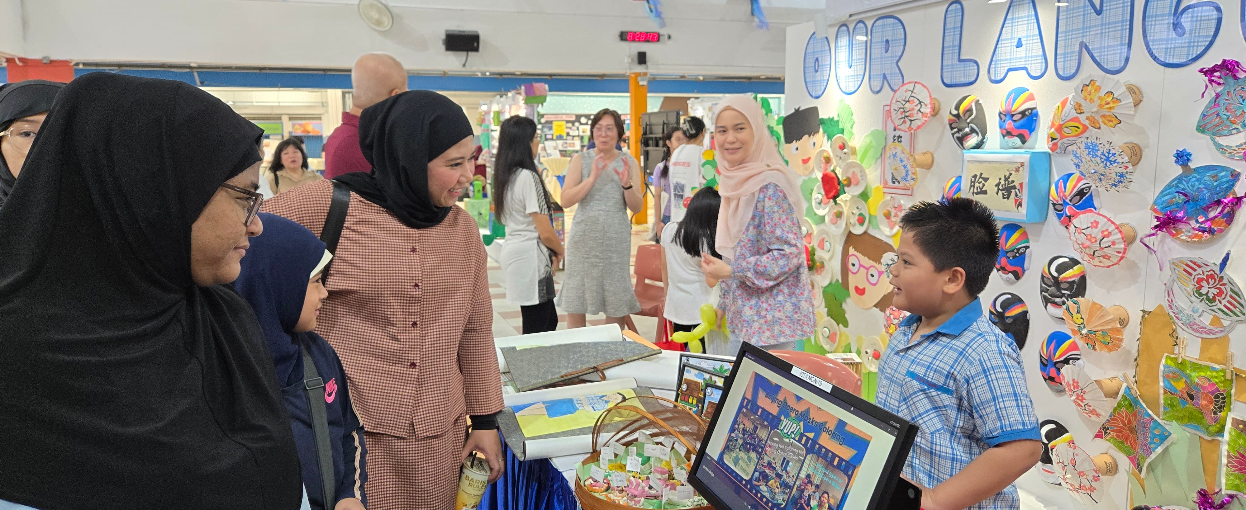 Students and visitors view multilingual posters promoting water conservation at the Mother Tongue Language booth during the 40th Anniversary celebrations