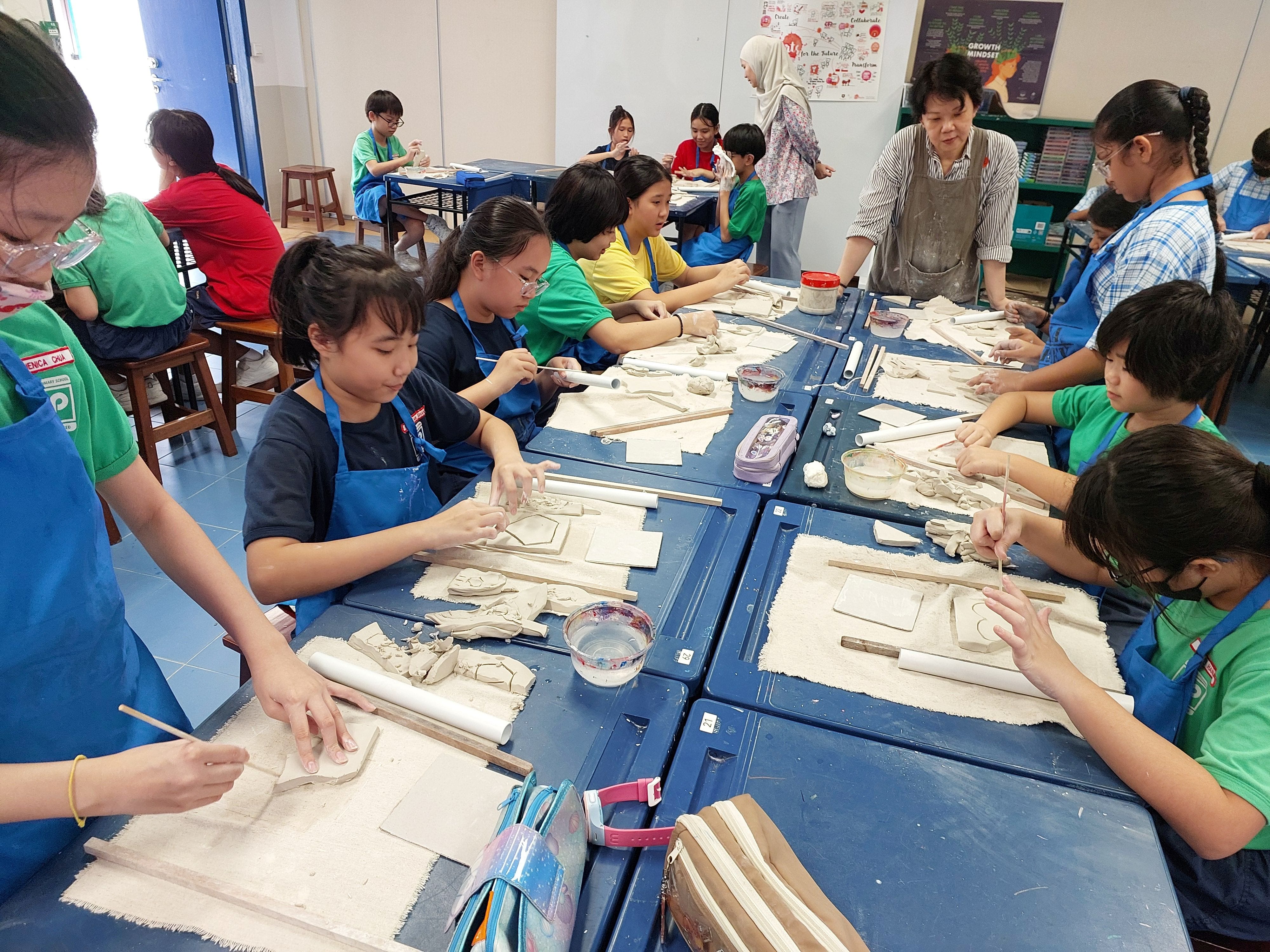 Art Club students create clay artworks under the guidance of their instructors.