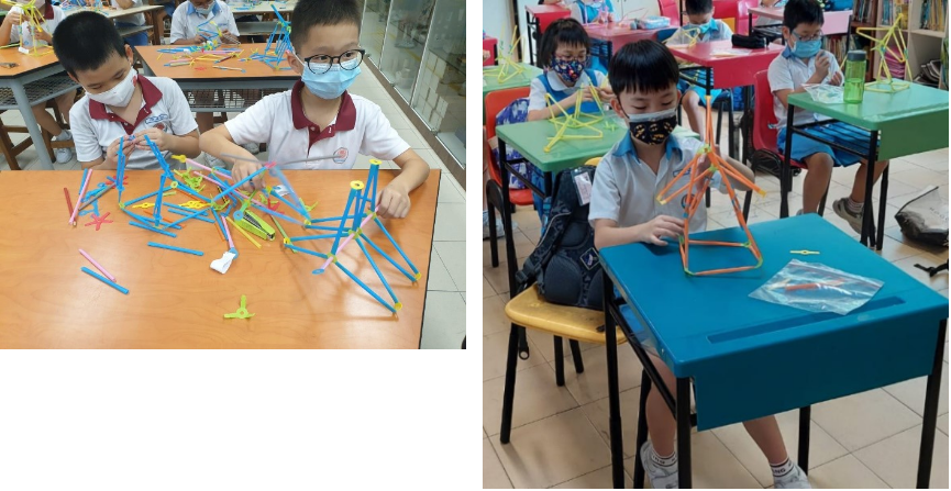Children wearing masks build structures with colorful plastic straws and connectors at school desks.