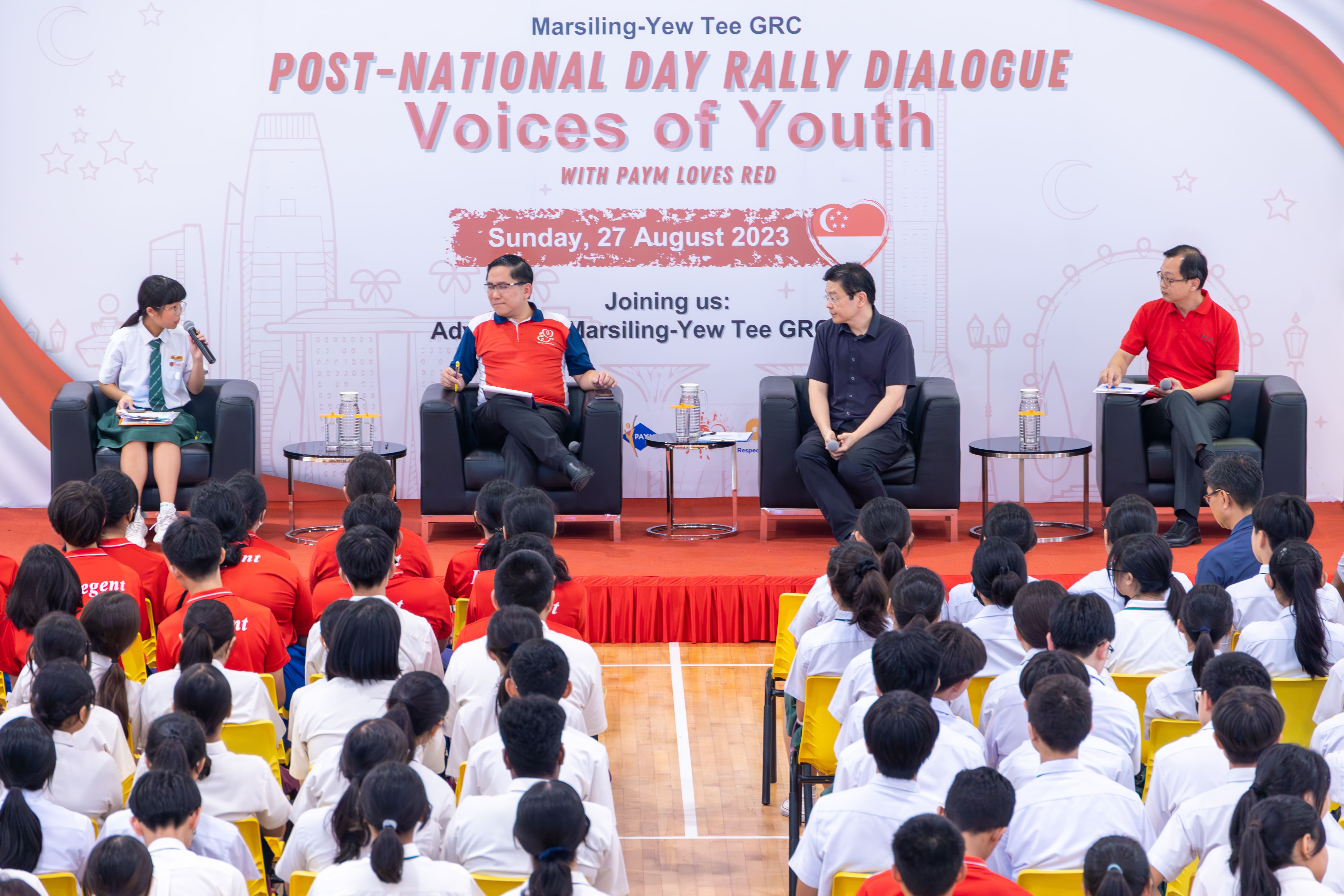 Four panelists seated on stage address a large youth audience at a Marsiling-Yew Tee GRC dialogue on 27 August 2023.
