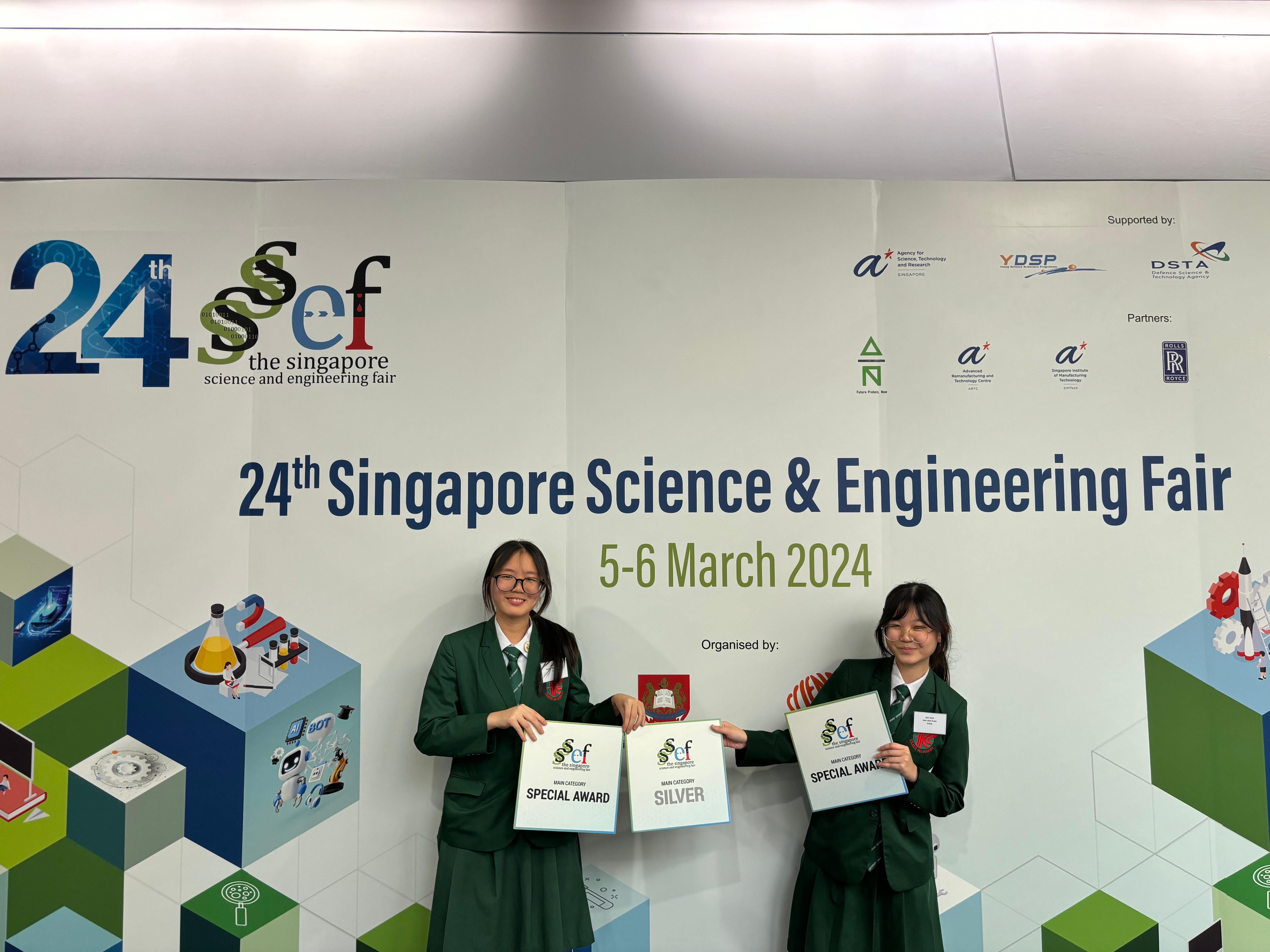 Two students in green uniforms hold Special Award and Silver certificates at the 24th Singapore Science and Engineering Fair 2024.