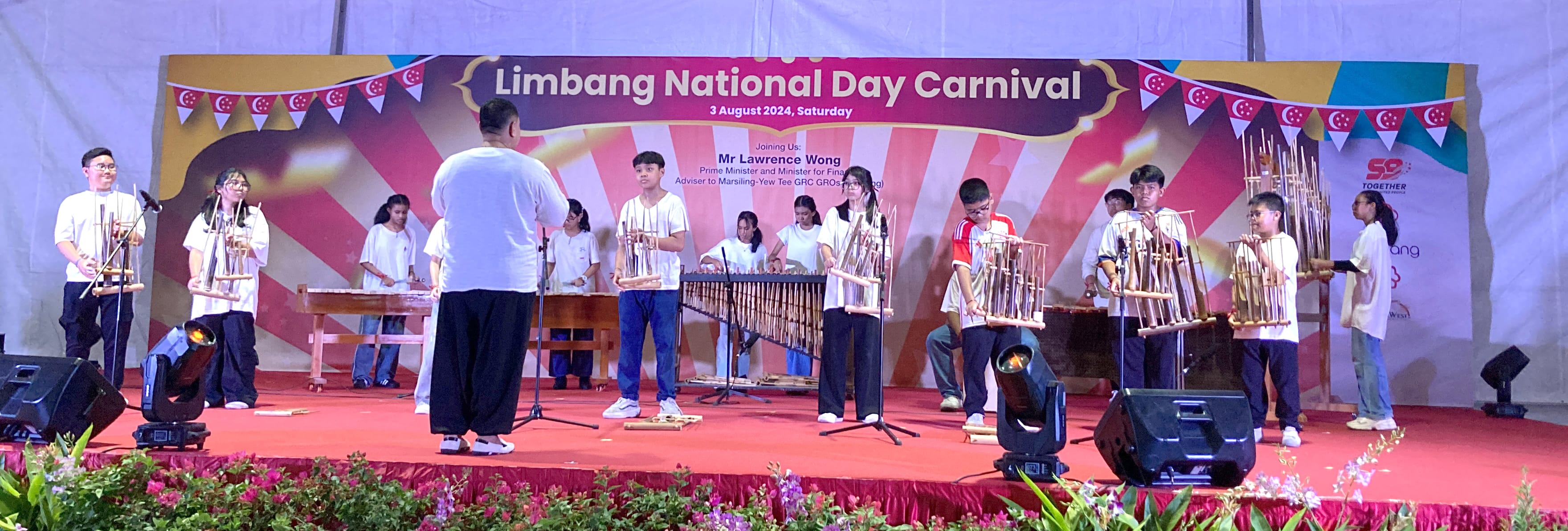 Students play traditional bamboo instruments on a red stage at the Limbang National Day Carnival on 3 August 2024.