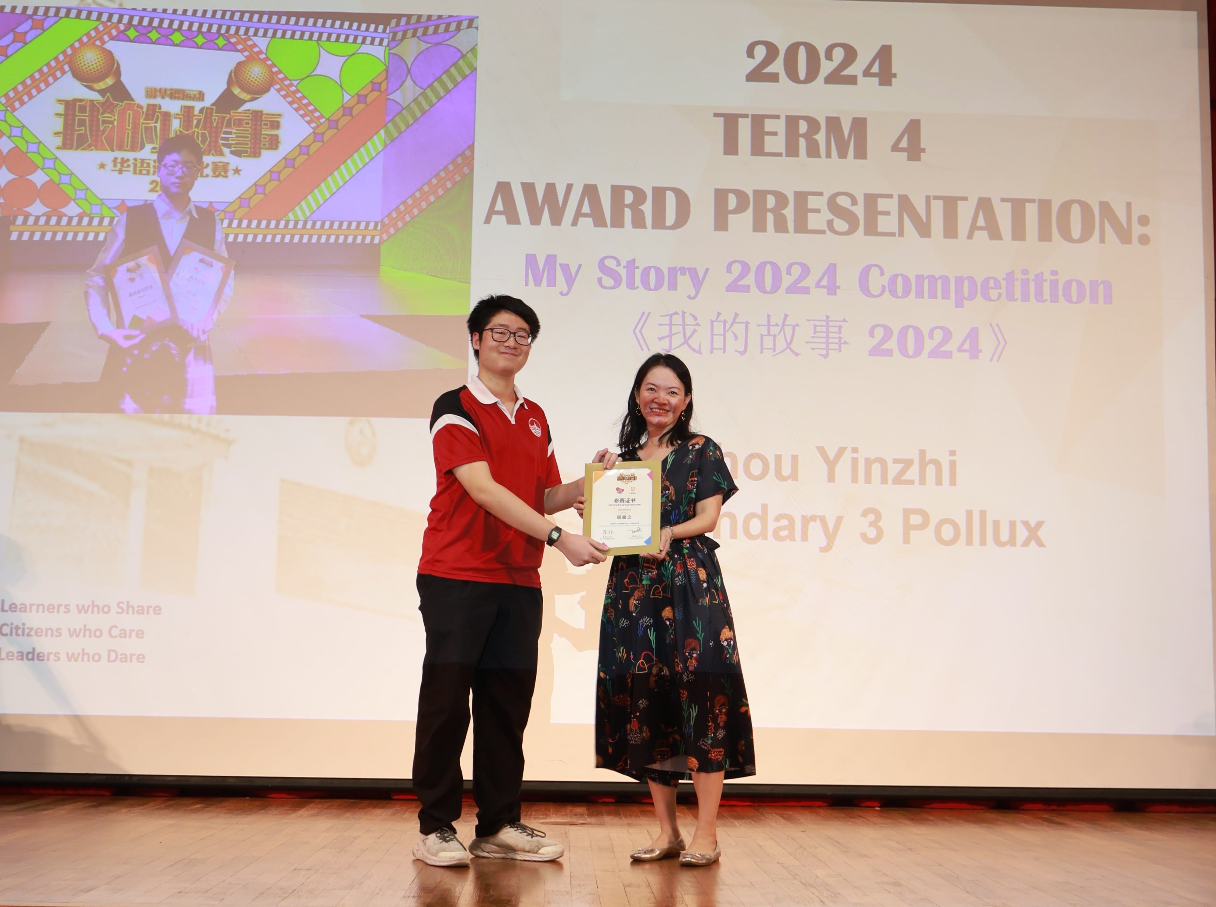 Two people stand on a stage holding a certificate at the 2024 Term 4 My Story Competition award presentation.