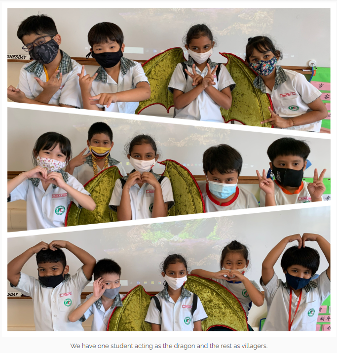 Three rows of masked schoolchildren in uniforms posing with a dragon costume prop, making peace and heart signs.