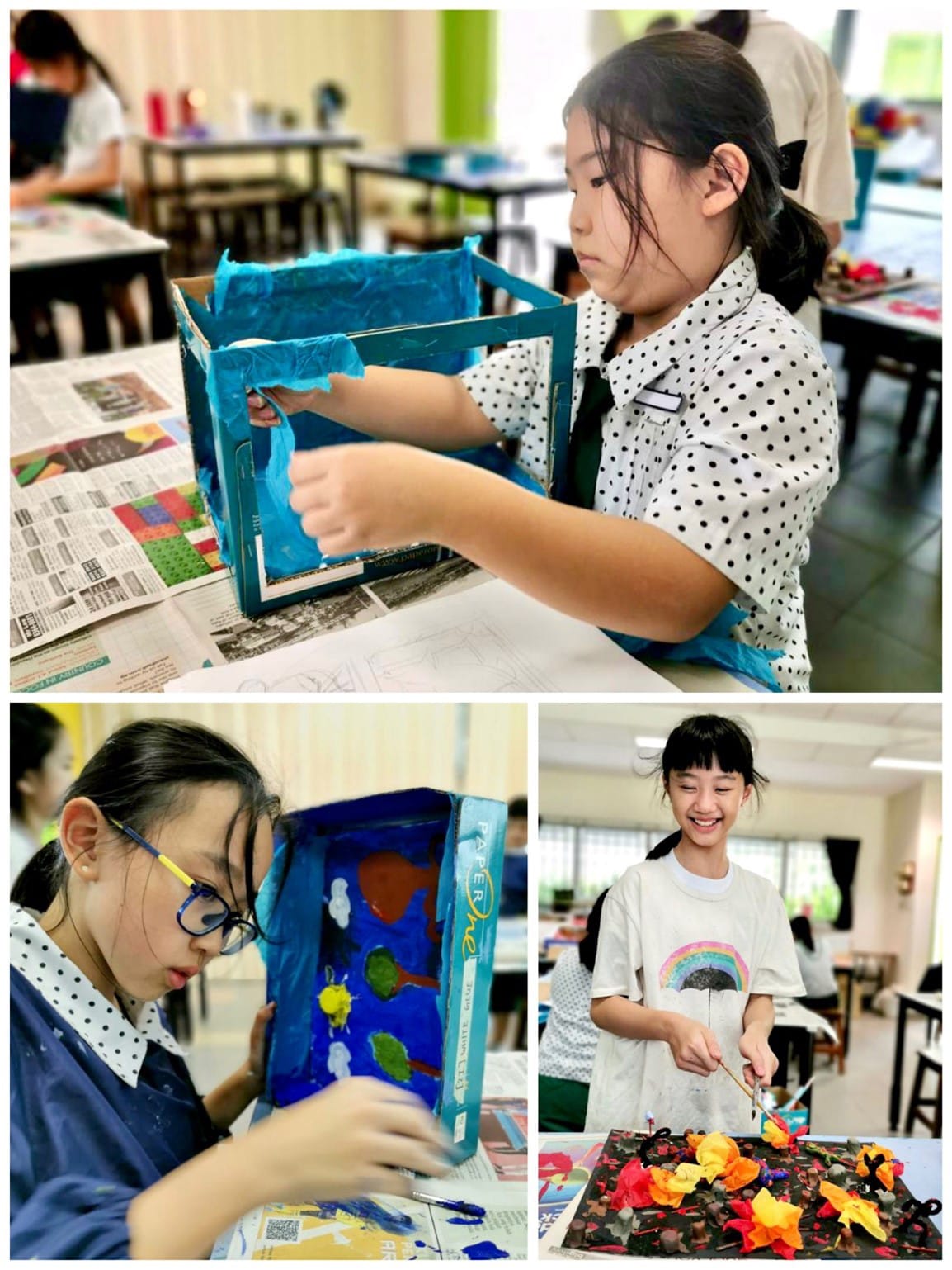 Three girls work on colorful art projects using painted cardboard boxes and tissue paper in a classroom.