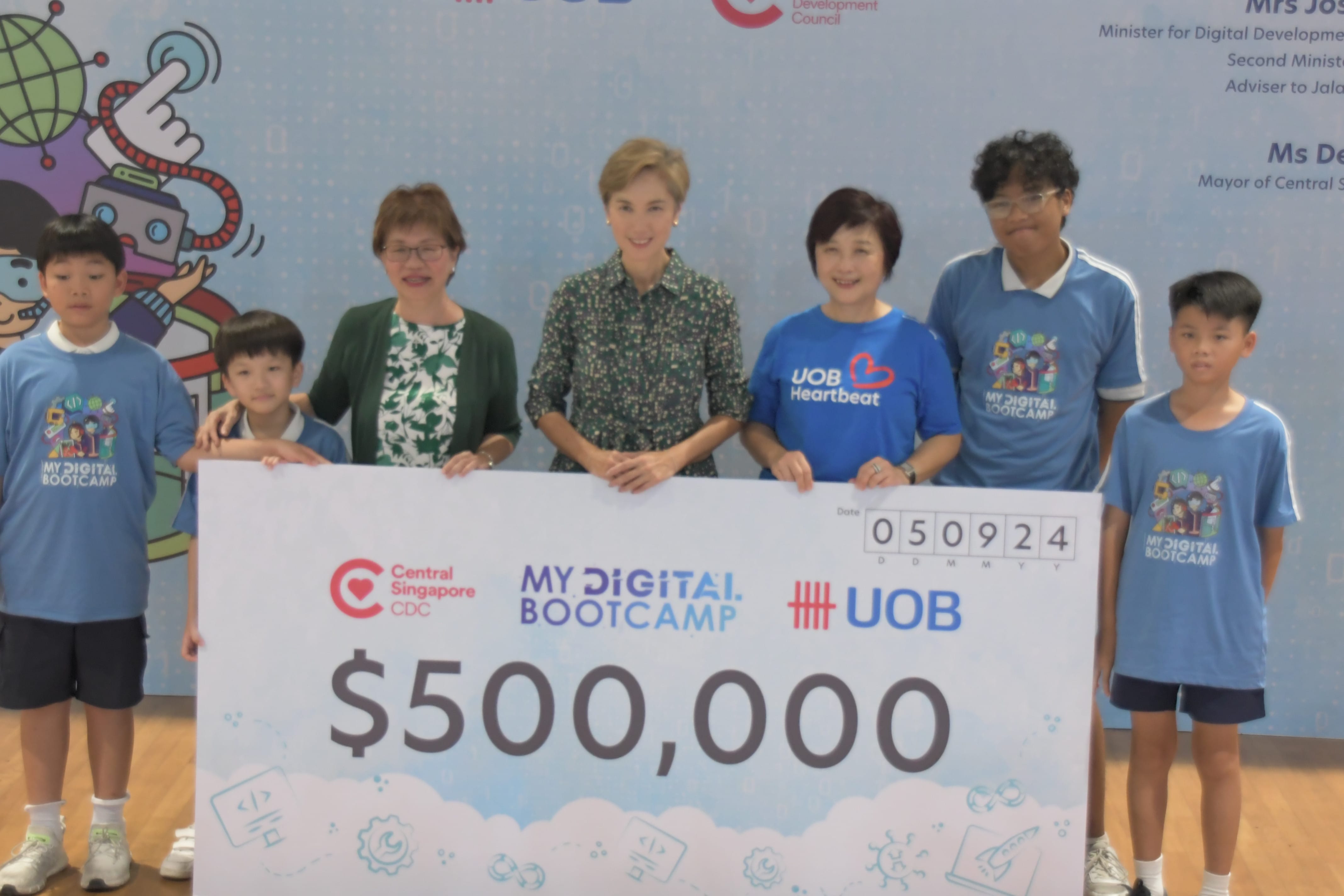 Adults and children hold a large ceremonial check for $500,000 from UOB for My Digital Bootcamp.