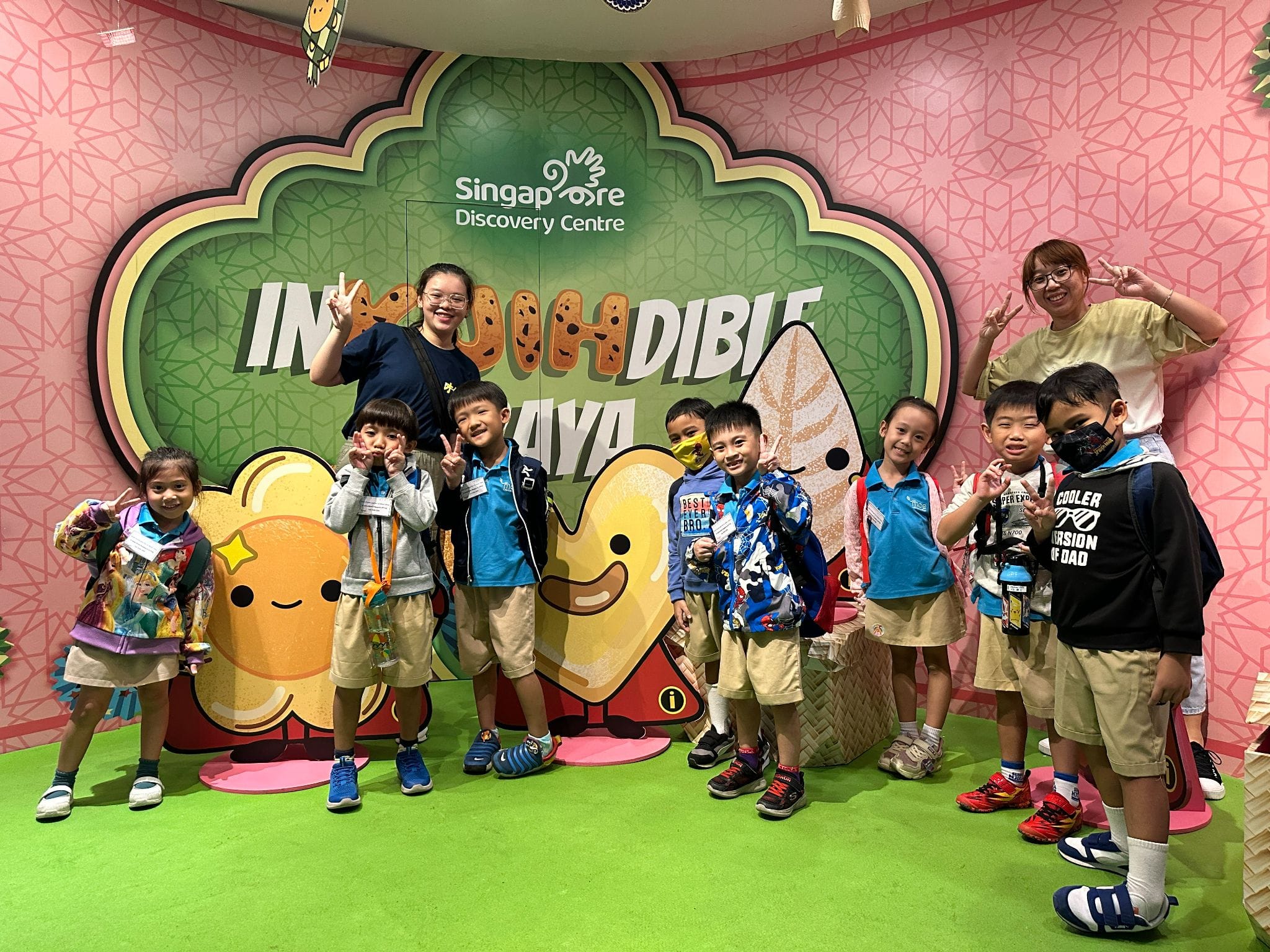 Group of young children and two adults posing at the Singapore Discovery Centre Incredible Kaya exhibit.