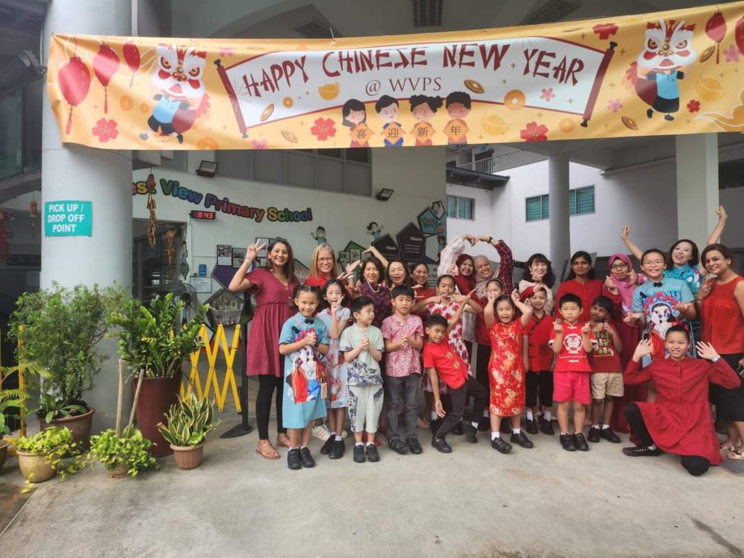 Group of children and adults posing under a Happy Chinese New Year banner at West View Primary School.