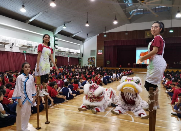 Students perform a lion dance in a school hall.