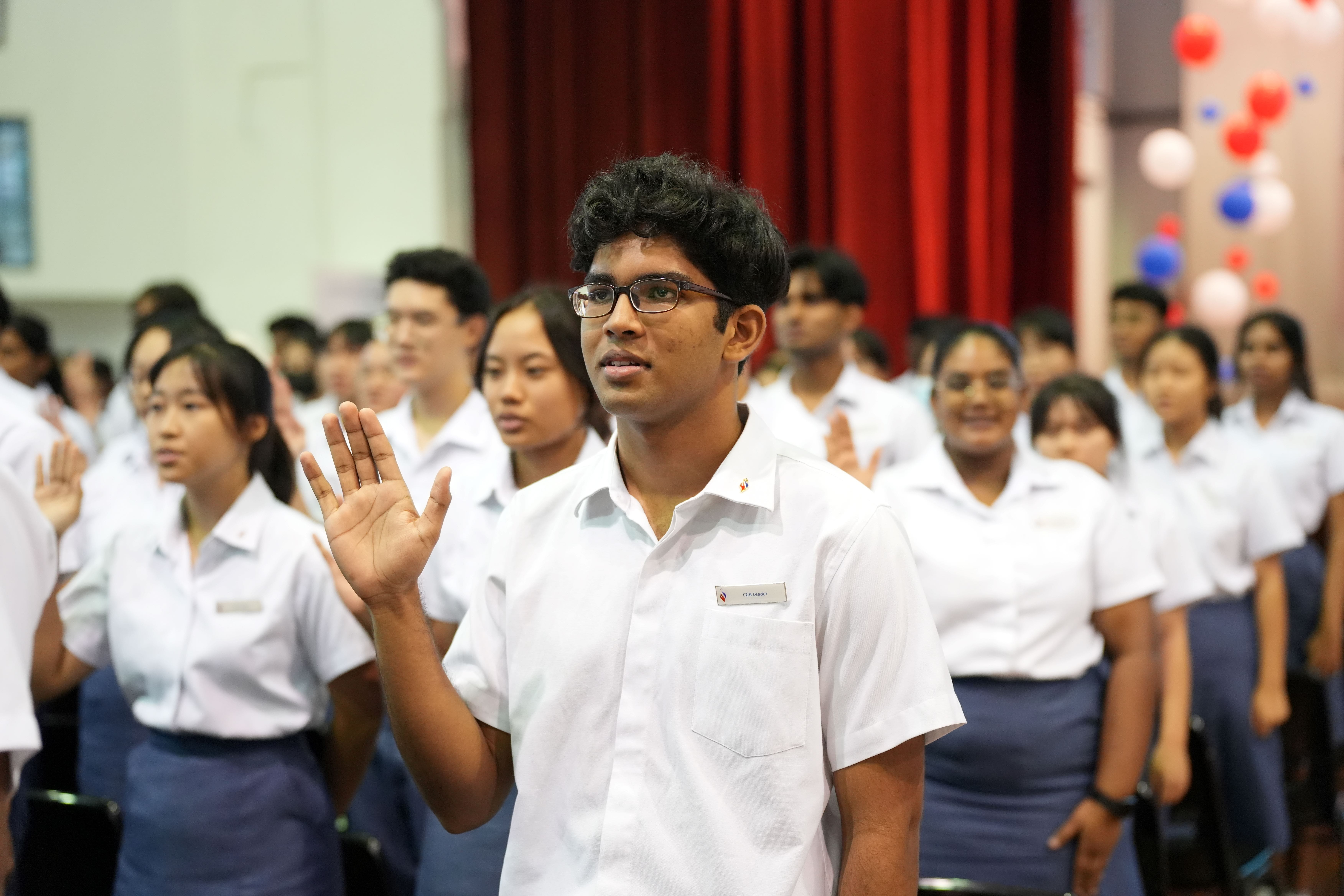 Students leaders raise their right hands during a pledge ceremony in a hall during the Student Leaders Investiture.