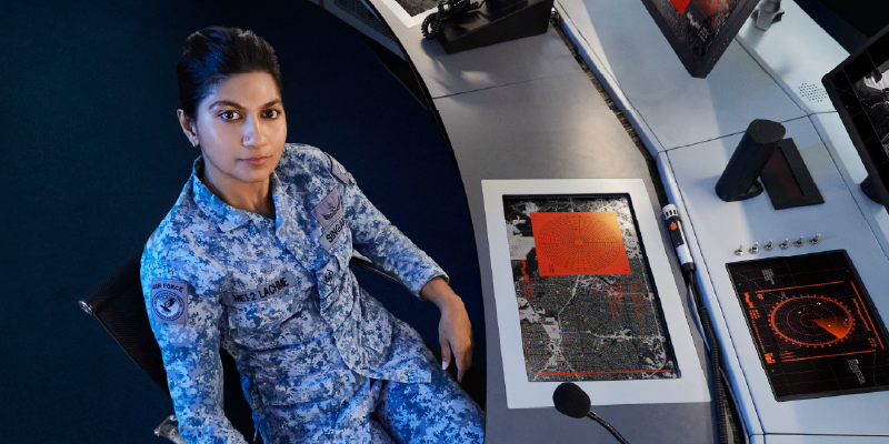 A female AOSX in uniform sitting at a workstation.