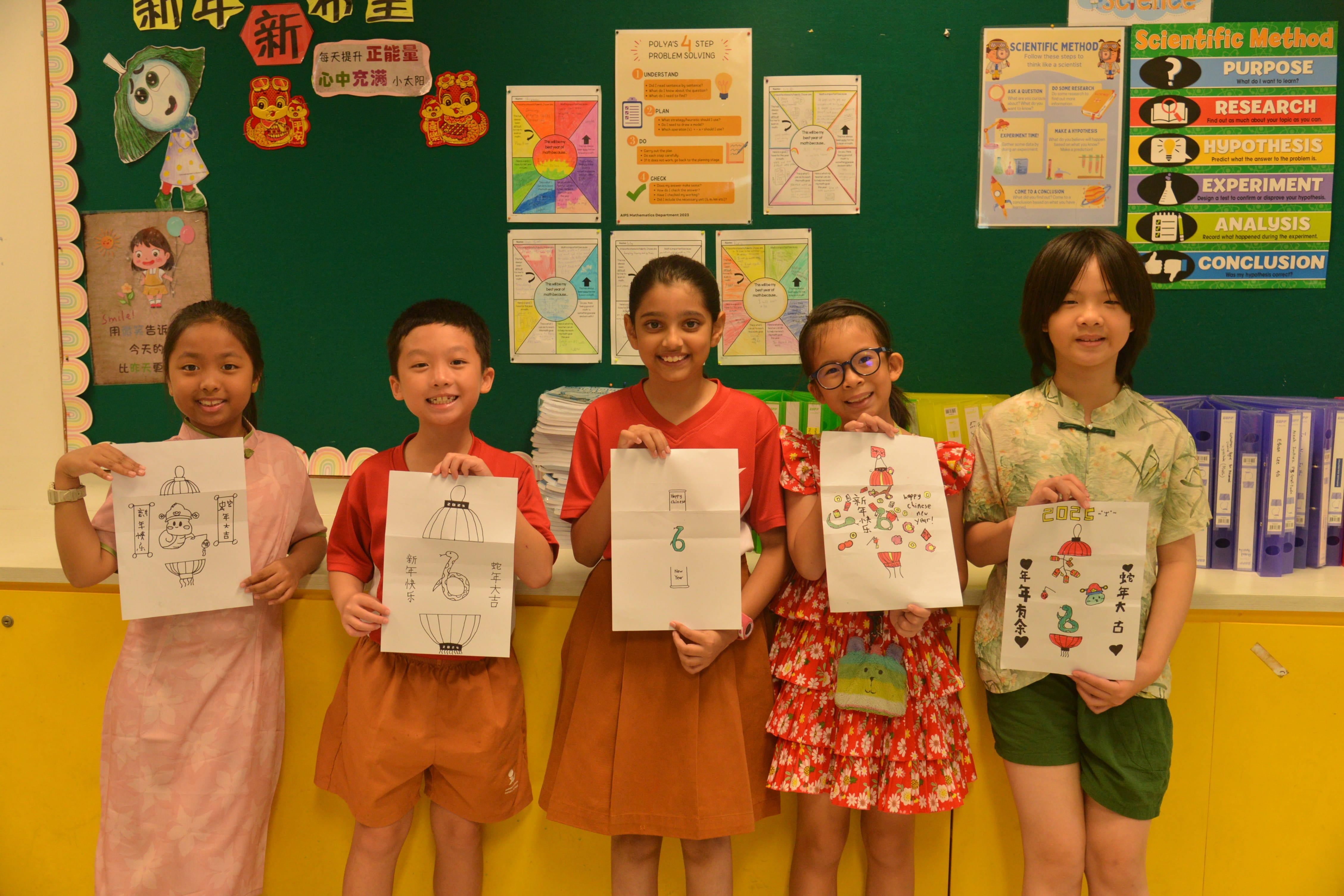 Five children stand in a classroom holding handmade Chinese New Year drawings with Chinese text and festive designs.