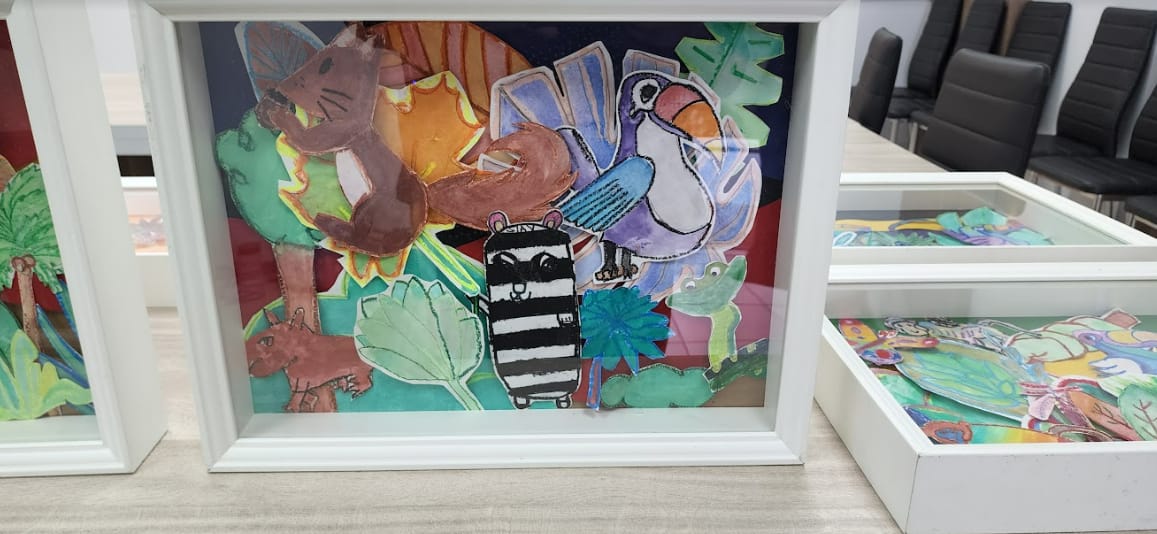 Framed children's artwork showing colorful painted animals including a raccoon, toucan, squirrel, and crocodile.