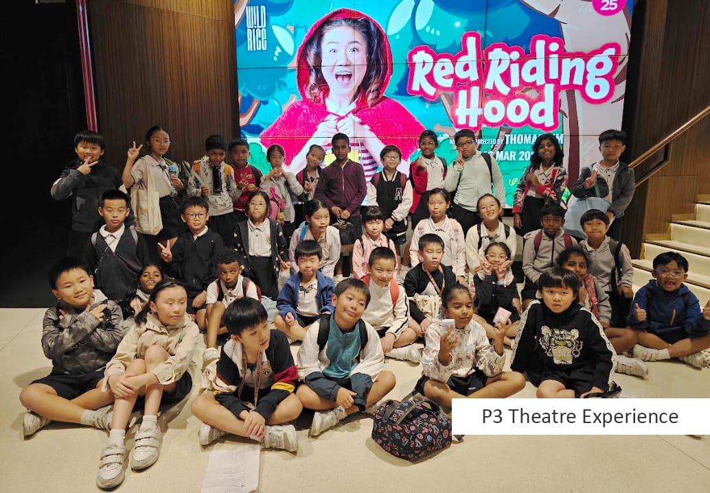 A group of children pose in front of a Red Riding Hood show poster during a P3 Theatre Experience.