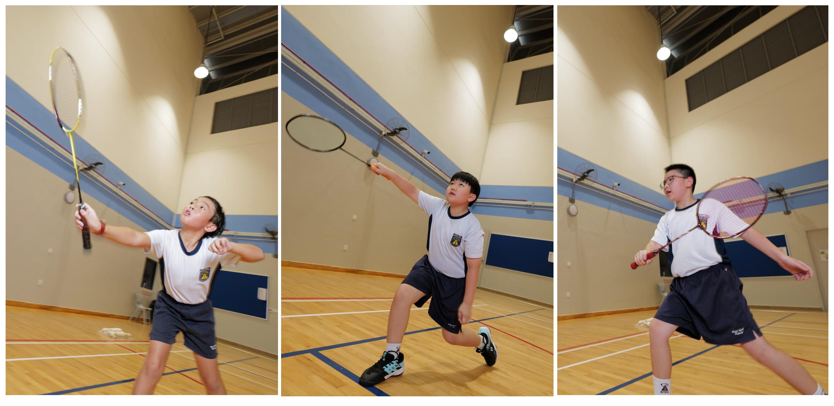 Three students play badminton indoors, each mid-swing on a wooden court.