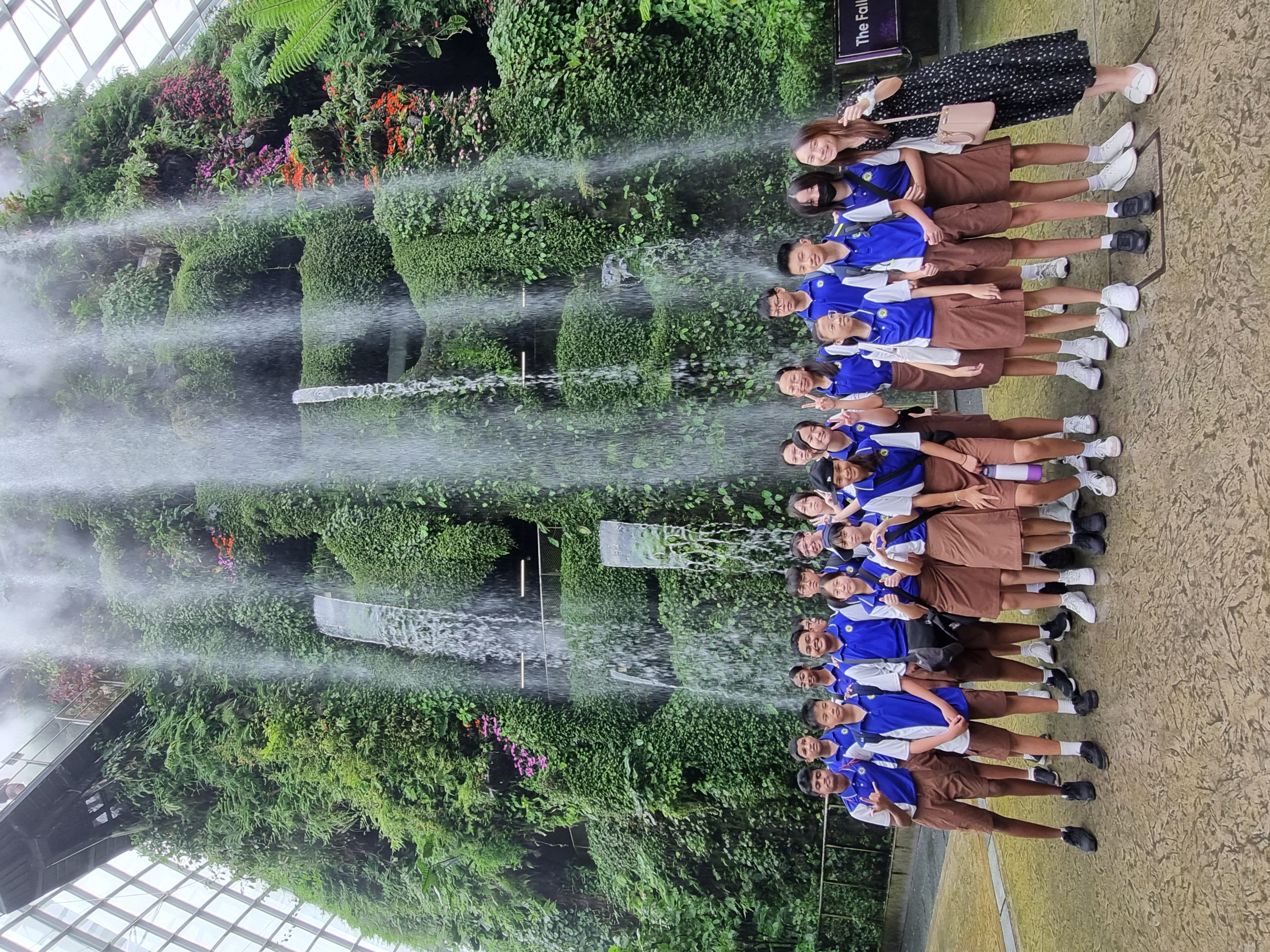 Students and staff posing in front of the indoor waterfall during a Nature and Sustainability Tour at Gardens by the Bay.