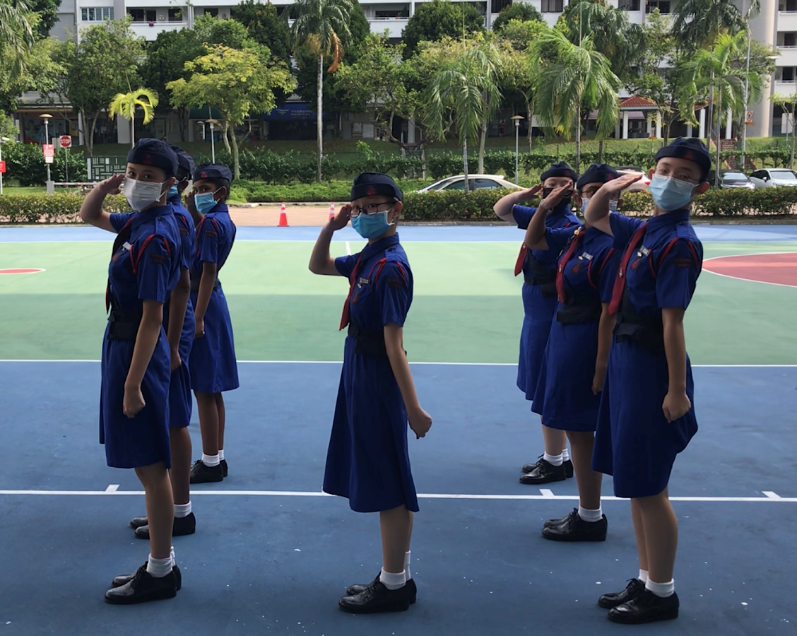 Girls’ Brigade members in uniform practising drill formations and saluting.