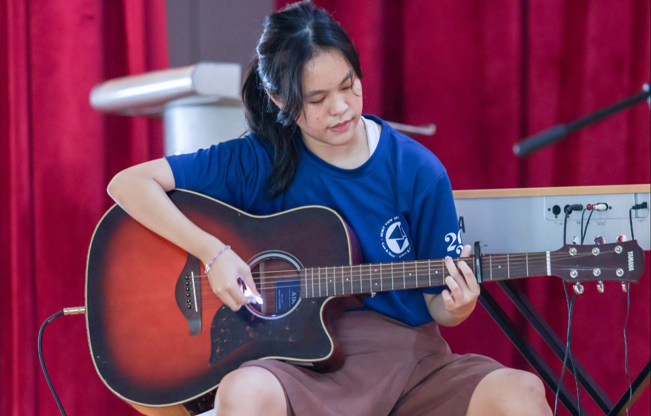Student performing on the guitar during a Youth Day performance.