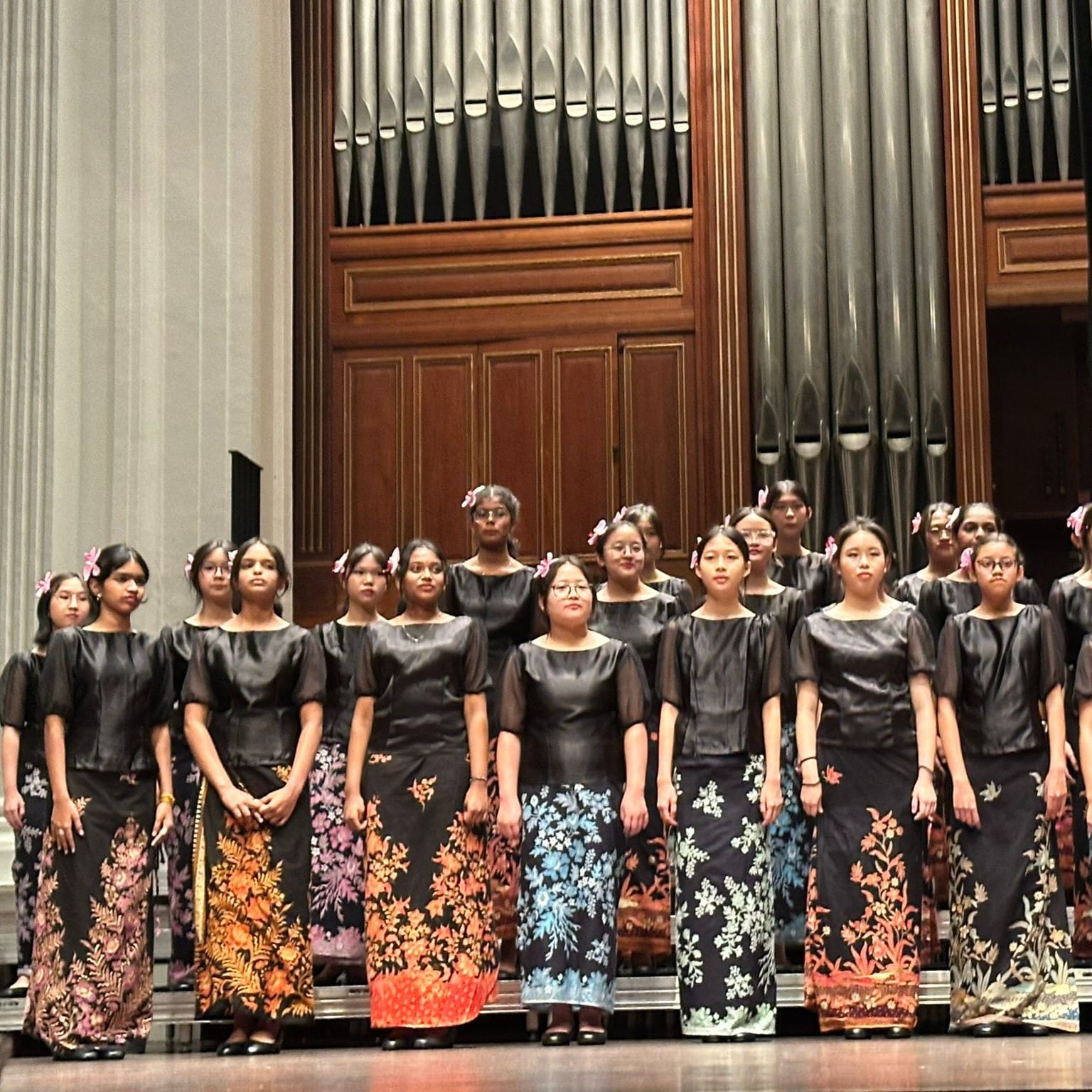 BVSS Choir members performing on stage in black tops and colourful batik-inspired attire at Victoria Concert Hall.