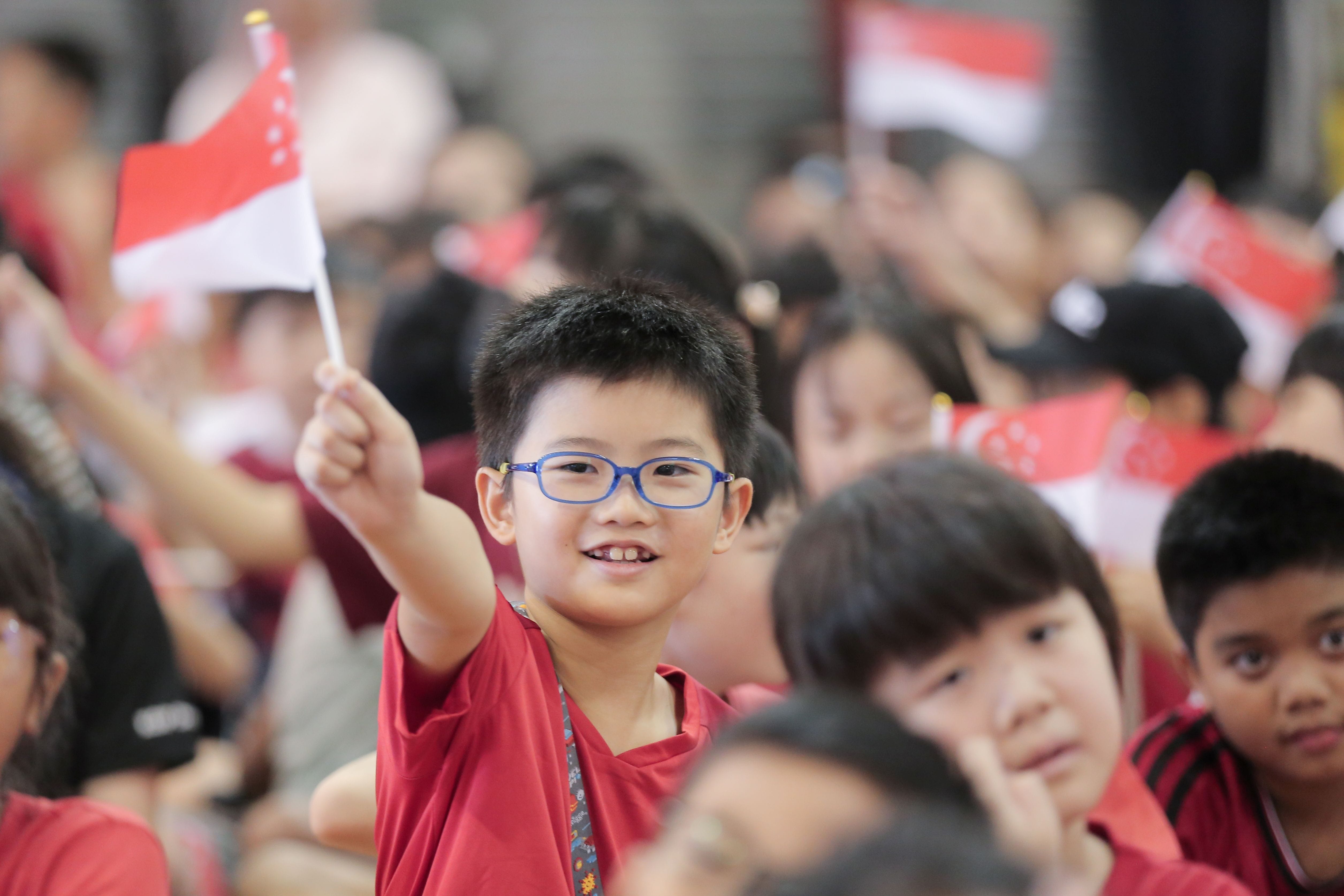 A student waving national flag during National Day Celebration